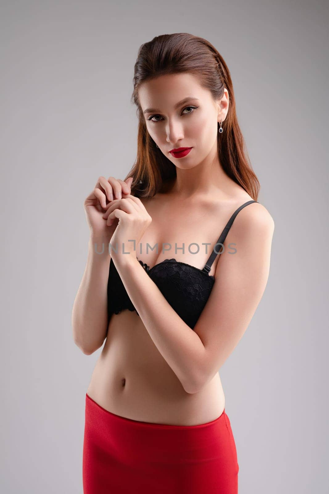 A woman displays confidence wearing stylish lingerie while showcasing her beauty in a well-lit studio setting.