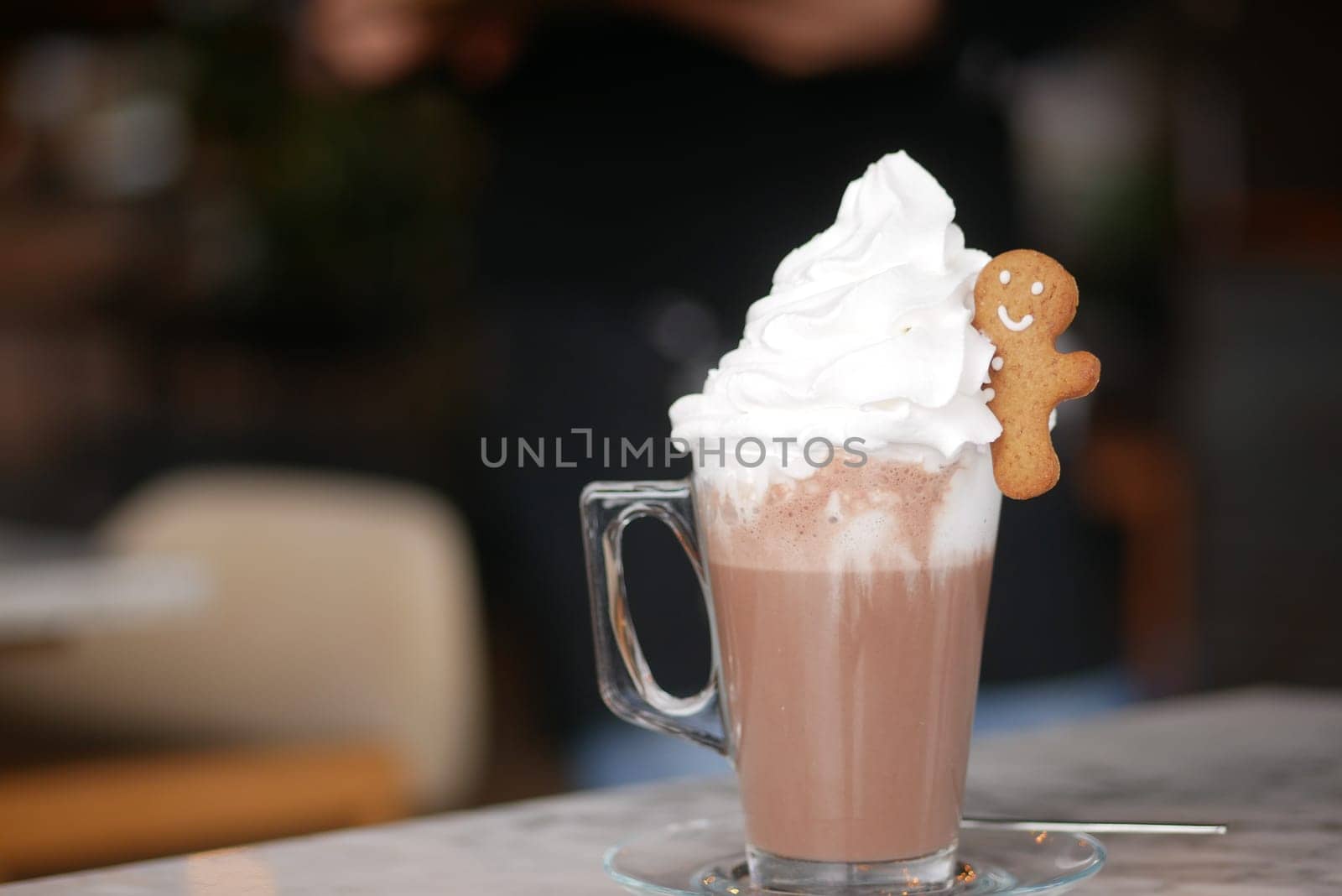 Delicious warm drink with whipped cream and cookie sits on a table.
