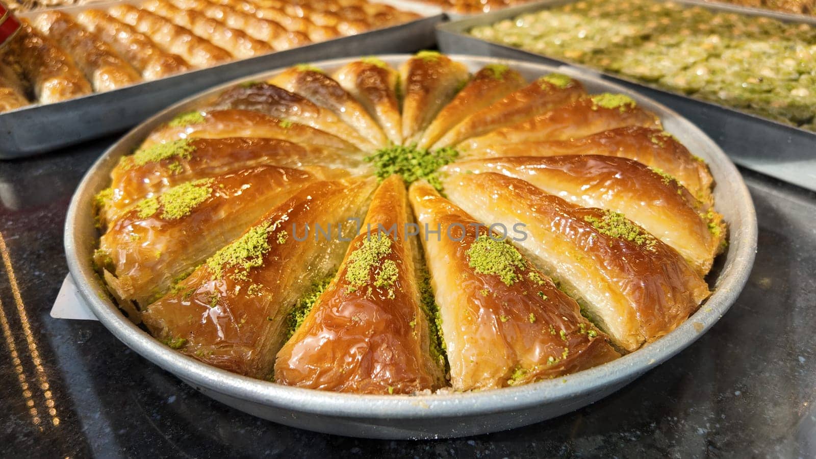 A tray of baklava filled with nuts and syrup sits in a bakery for sale.