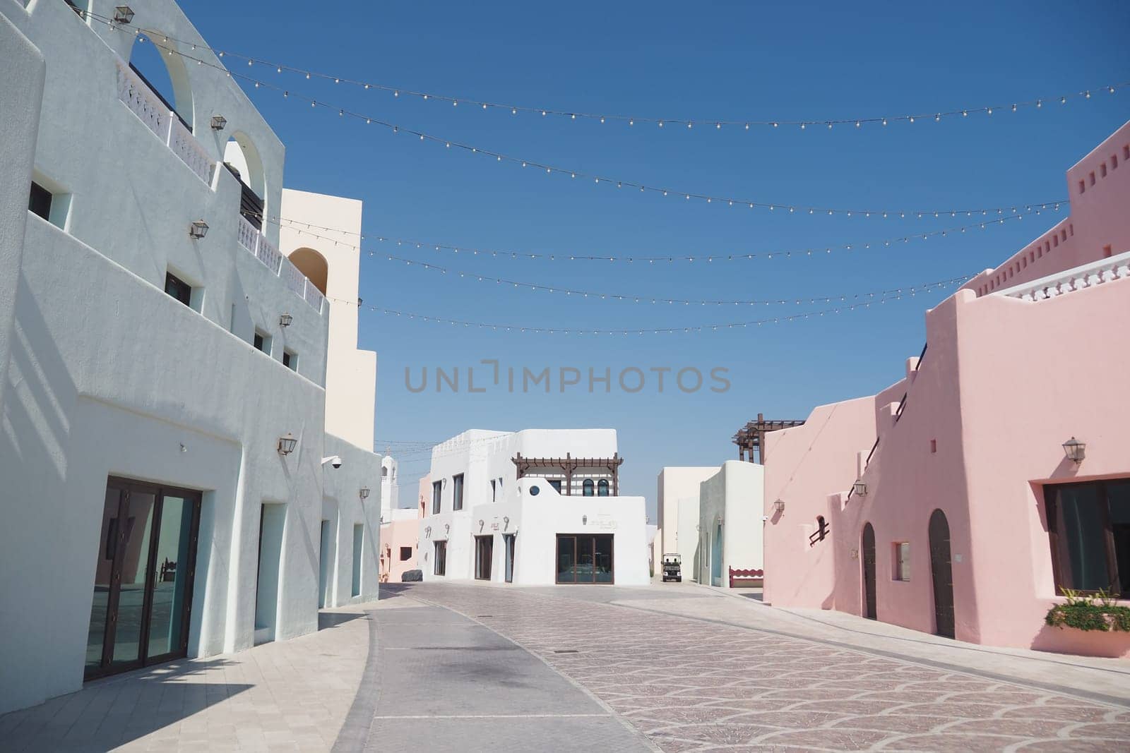 Brightly colored buildings line the pathway in a sunlit town.