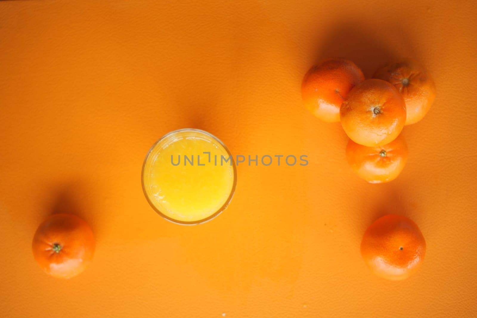 Bright orange background features a glass of fresh juice and several oranges.