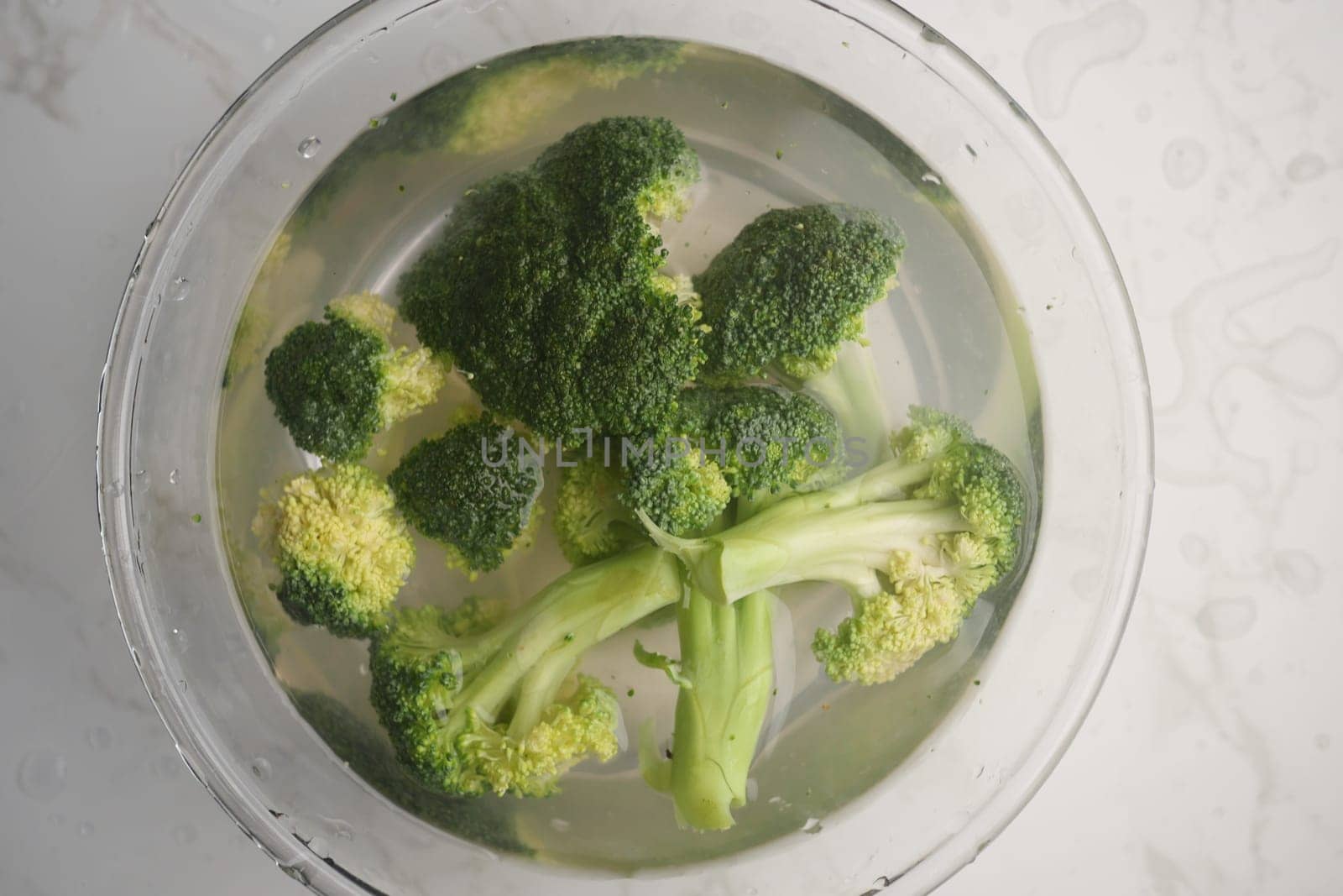 Fresh broccoli is soaking in water to clean and prepare for cooking.