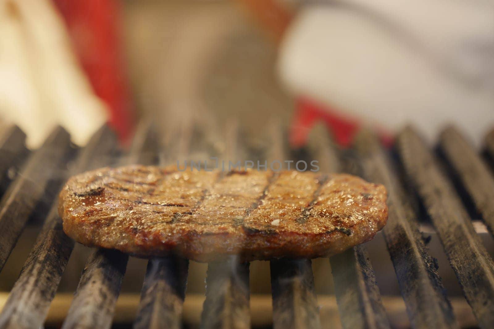A thick, grilled steak sizzles on a barbecue in a backyard setting.