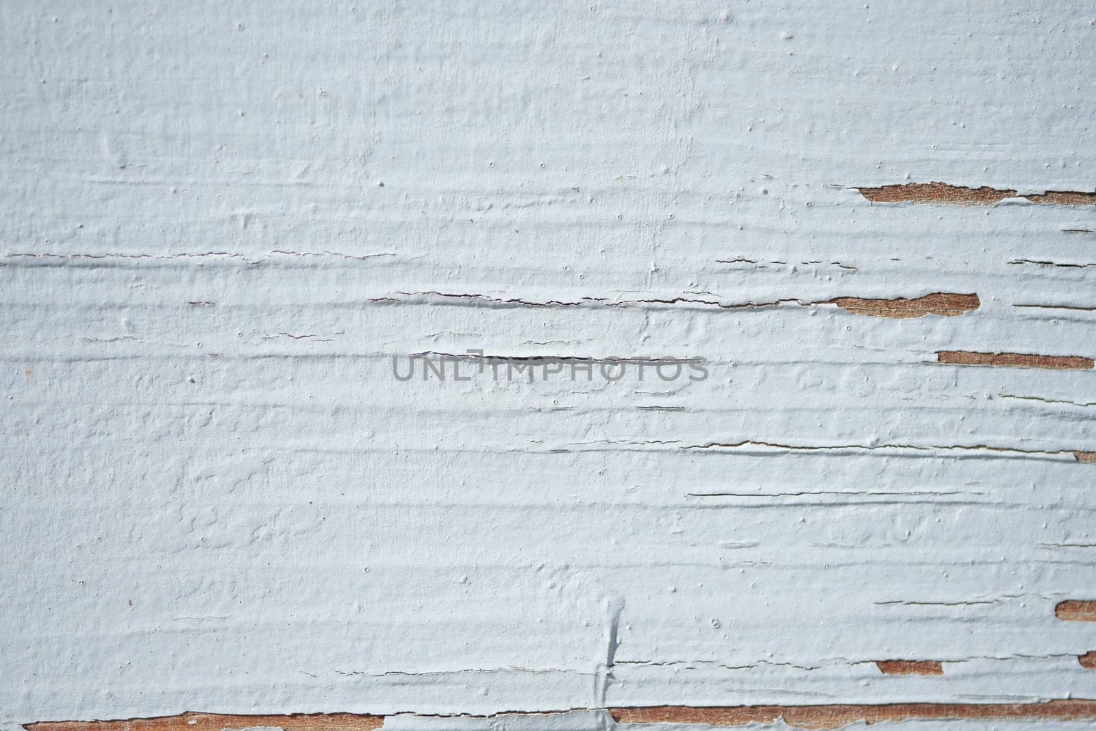 A close-up view of a weathered wall showing peeling white paint.