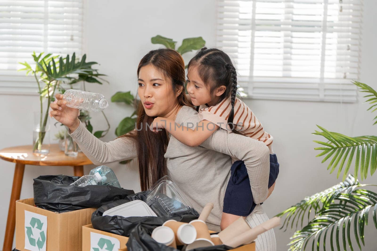 A mother enthusiastically teaches her daughter about the importance of recycling, creating a memorable and impactful bonding experience.