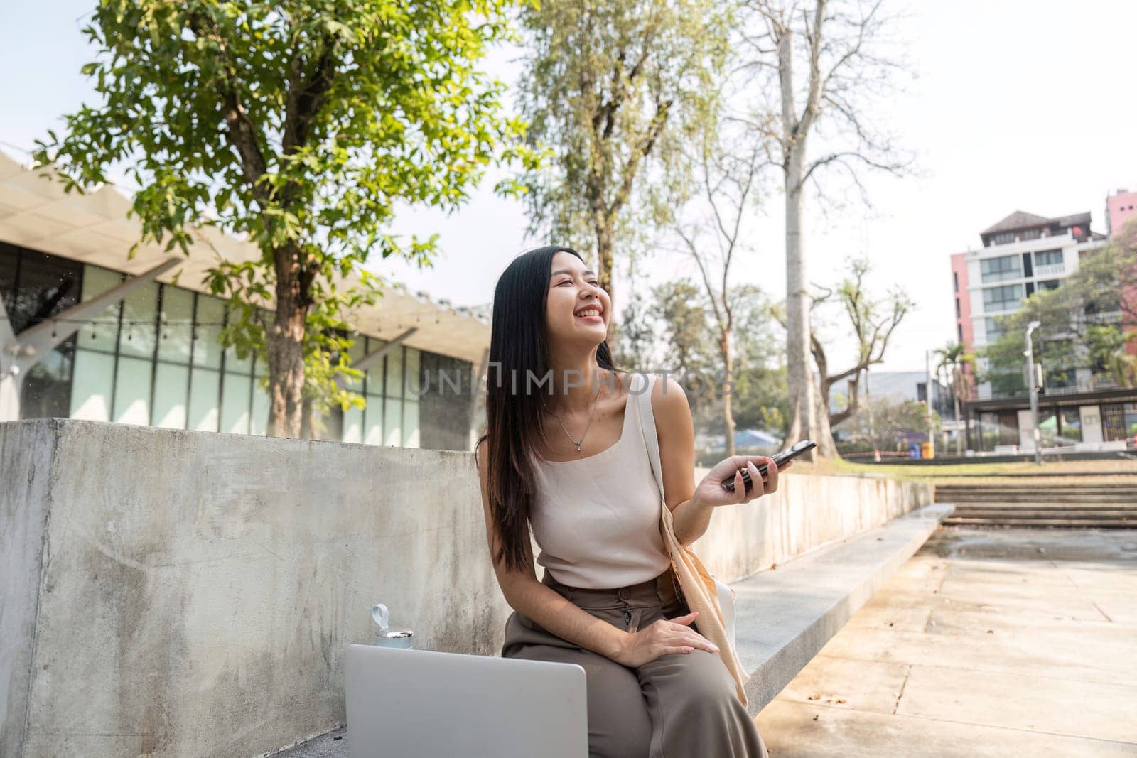 A young woman radiates happiness as she uses her smartphone, embodying a sustainable lifestyle in a vibrant outdoor space.