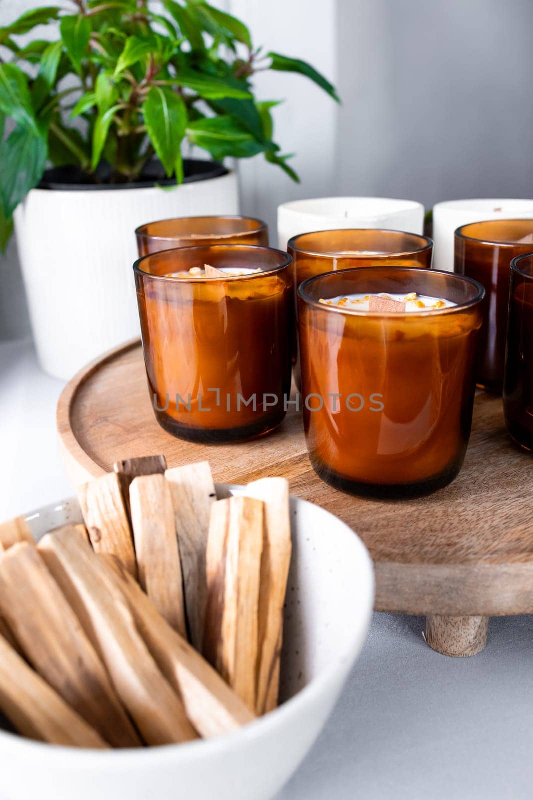 Aromatherapy candles and palo santo on wooden tray for relaxing ambiance.