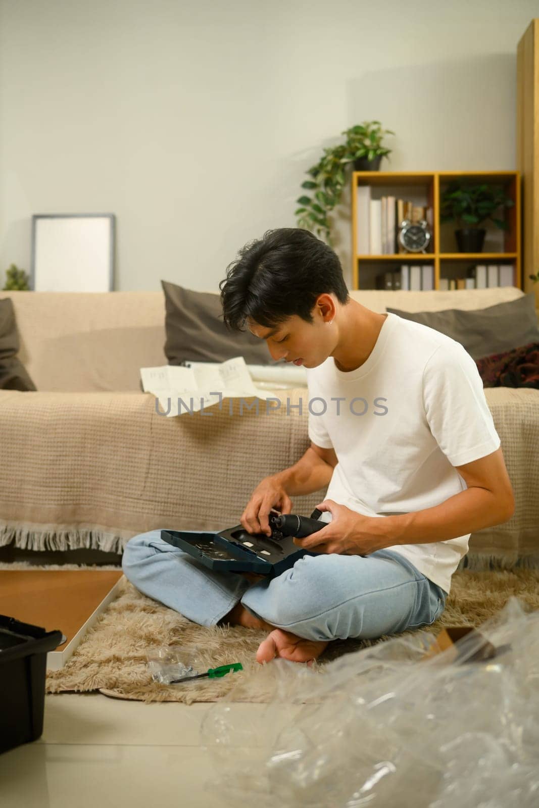 Young man selecting a tool from a drill set preparing to assemble furniture.