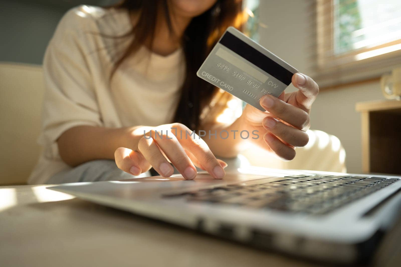 Close up shot of woman making an online payment with credit card and laptop at home.