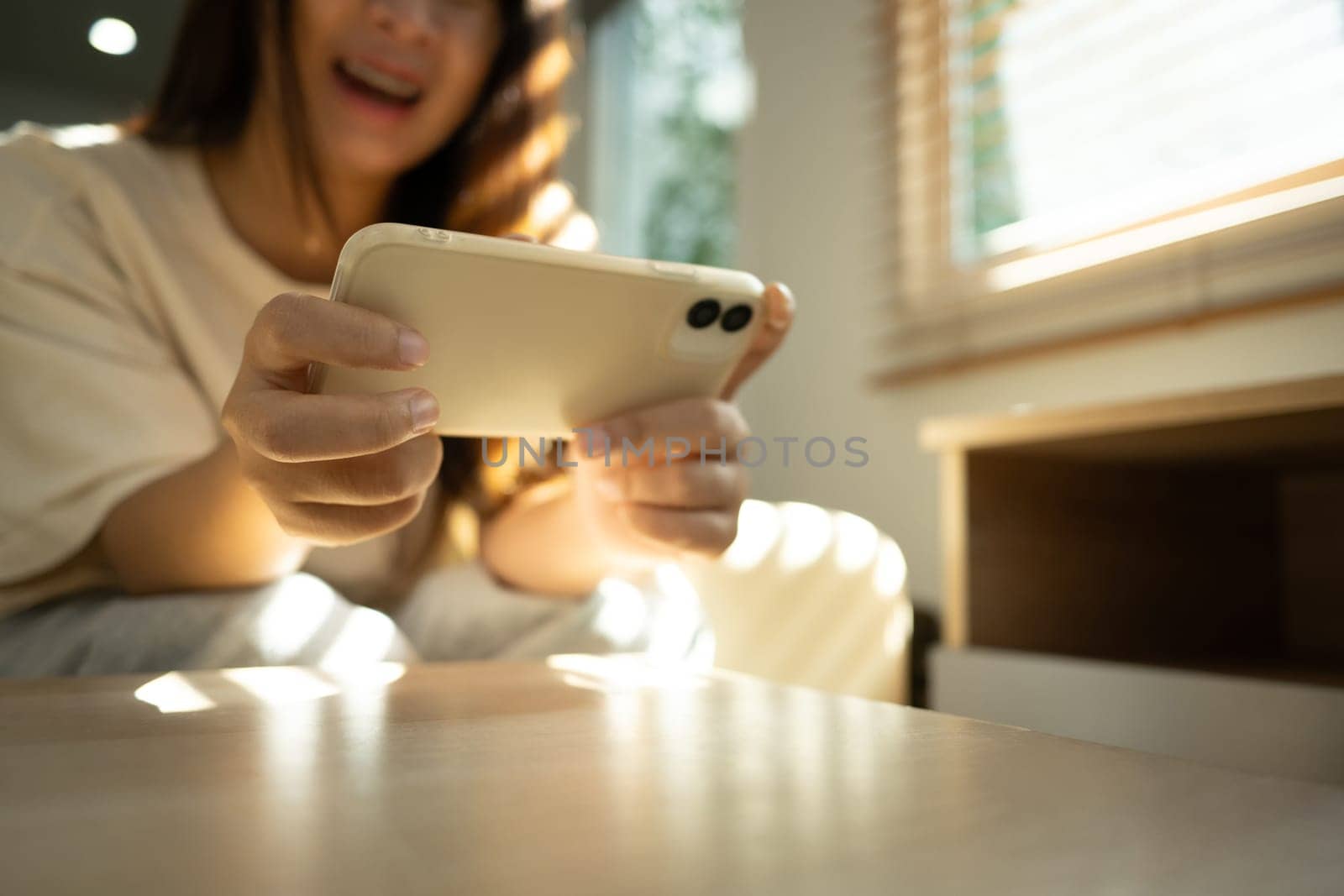 Excited woman playing a game on her smartphone in bright living room.