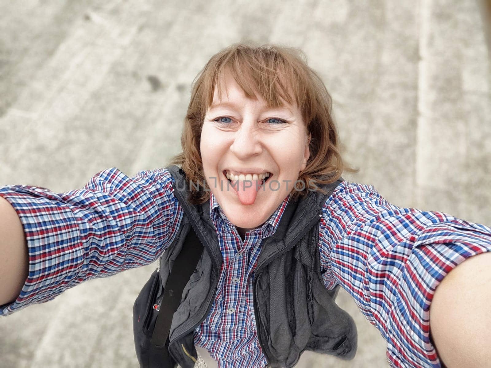 A middle-aged woman with blonde hair happily takes a selfie, capturing her joyful spirit during her travels.