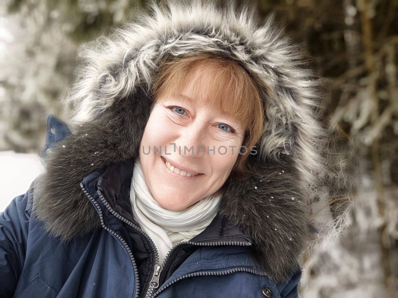 A woman captures a cheerful selfie in a snowy setting, showcasing her joy as a tourist enjoying the winter landscape during her adventure.