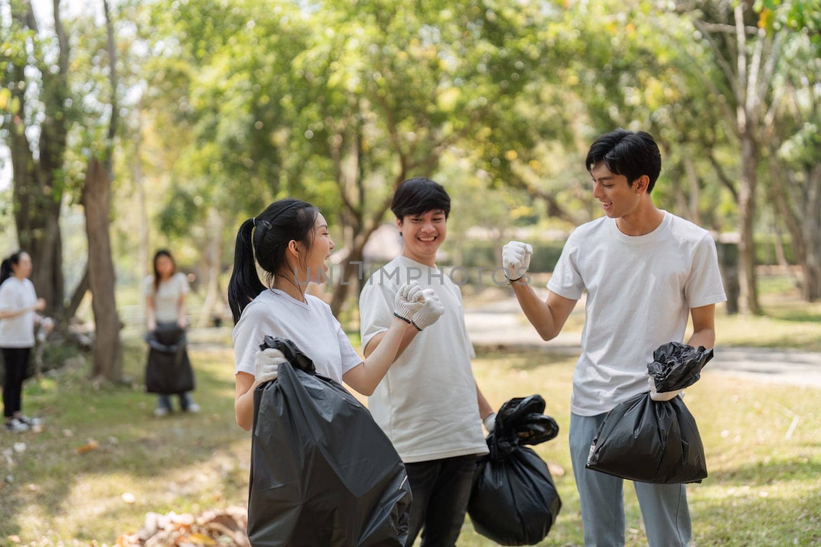 Three young volunteers share a joyful moment after collecting trash, promoting sustainability and teamwork.