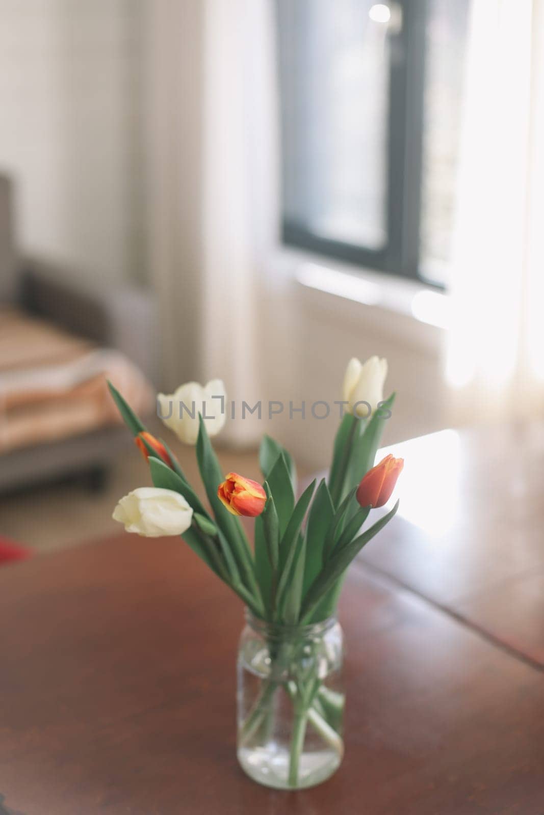 Beautiful bouquet of tulips in glass vase on table. Space for text. High quality photo