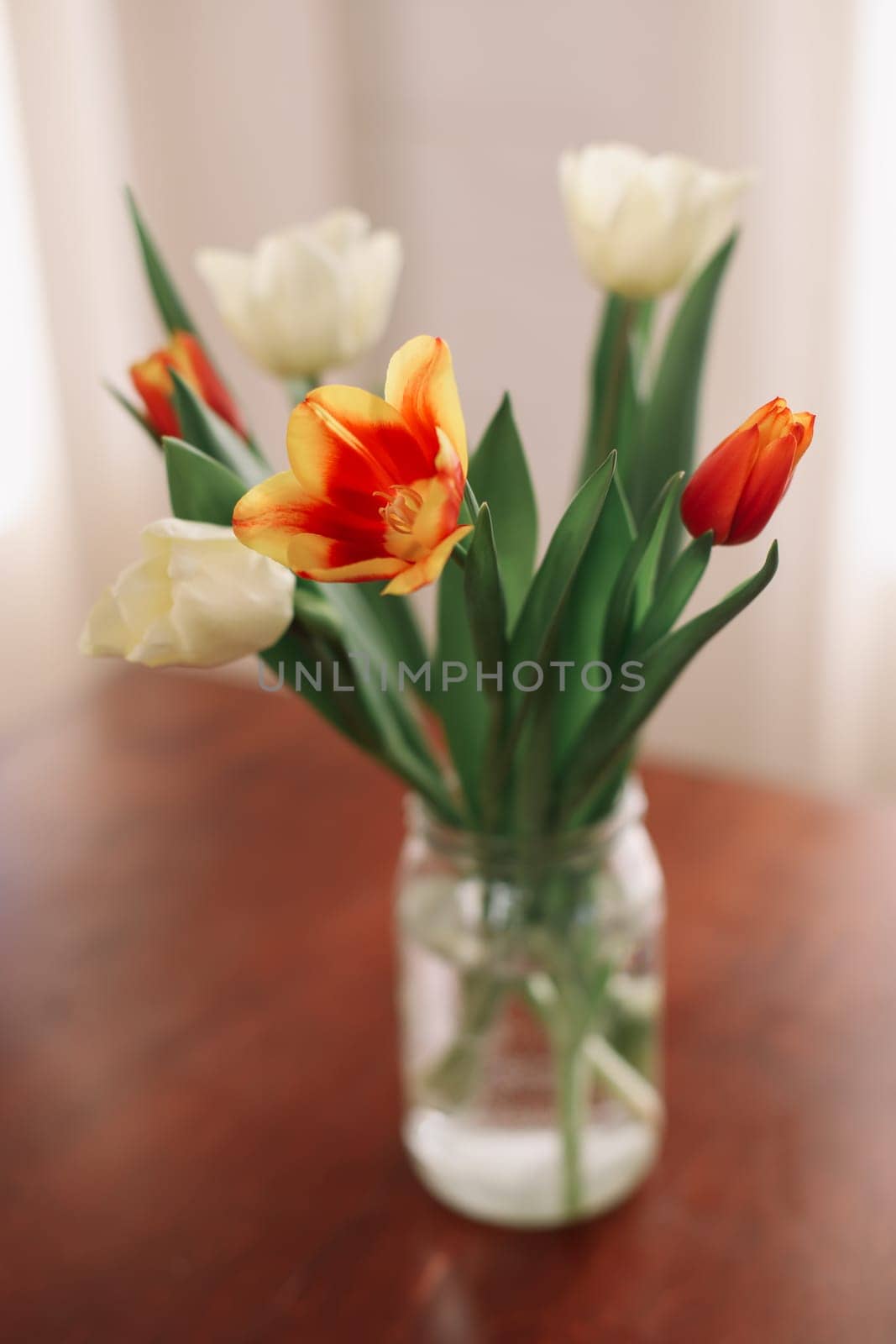Beautiful bouquet of tulips in glass vase on table. Space for text. High quality photo