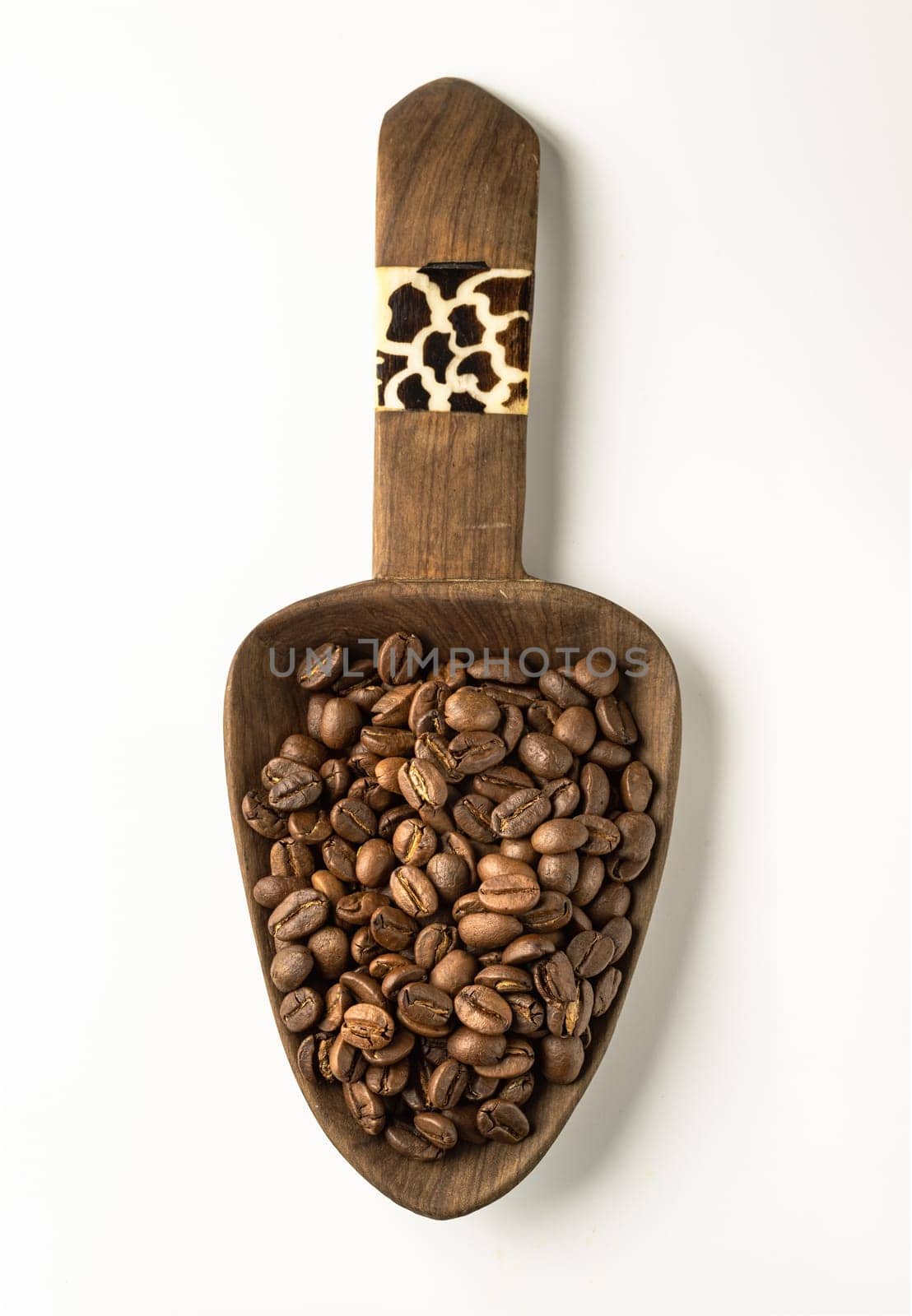 Top view of Roasted coffee beans on a rich textured surface in Wooden coffee scoop isolated on the white background. Enjoy your morning coffee for living, use it as your Space for text, Design, Wallpaper and Poster, Selective focus.