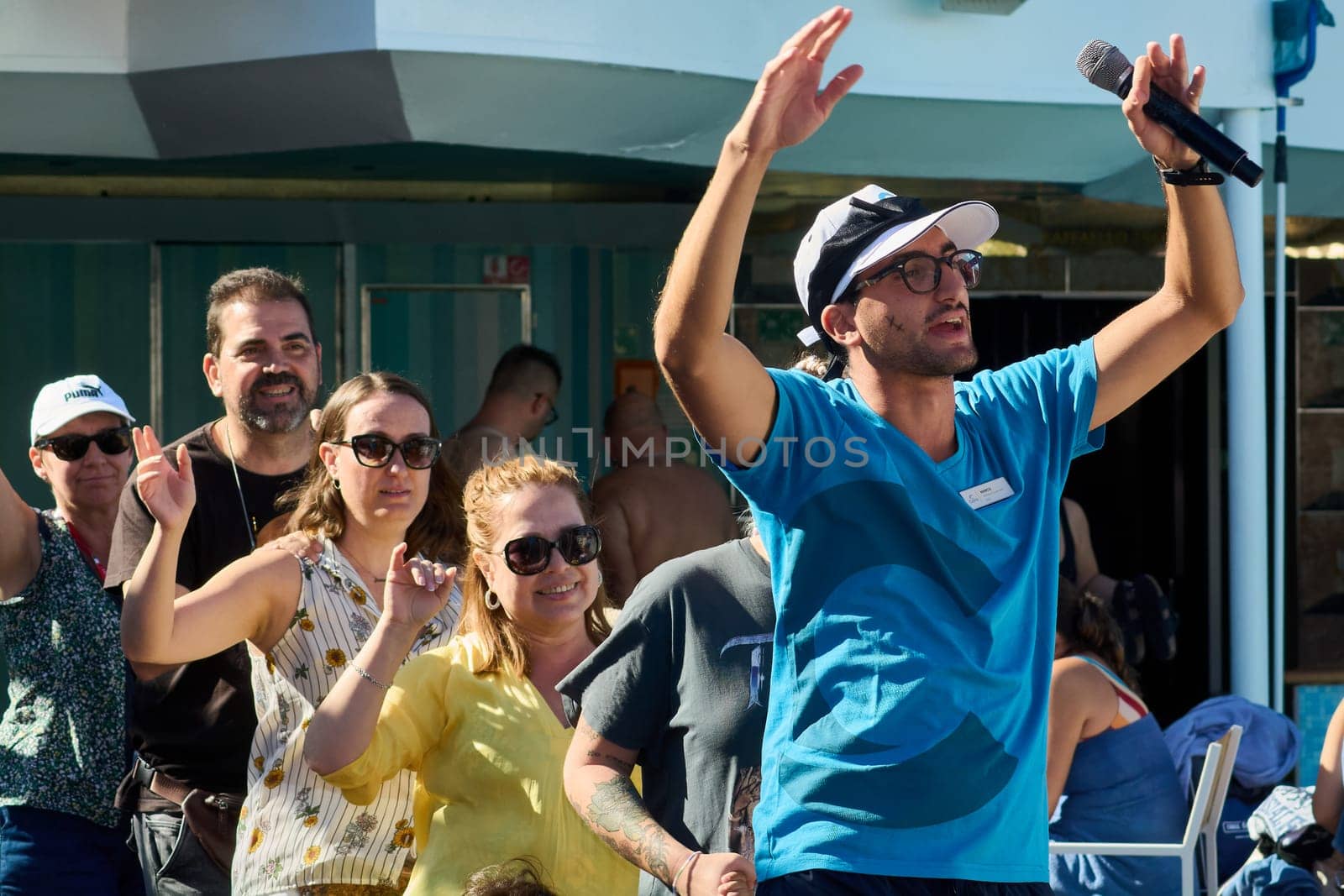 Catania. Italy - March 11, 2025: Vibrant scene of a performer interacting with attendees, leading activities while holding a microphone and showcasing event energy.