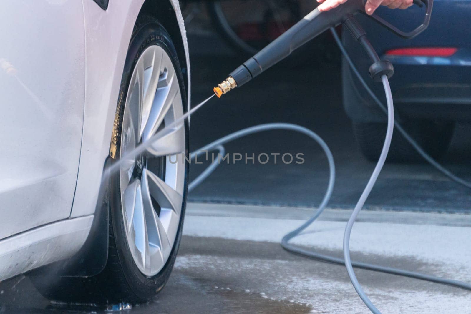 Denver, Colorado, USA-September 1, 2023-Efficiently cleaning an electric car in the comfort of a suburban driveway, combining eco-consciousness with practicality.