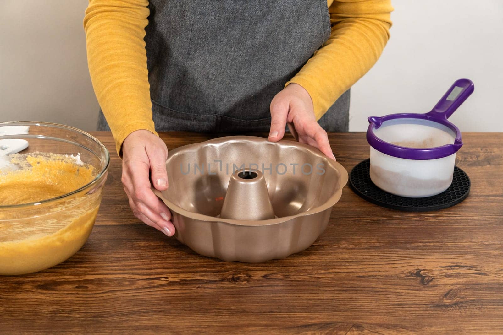 Carefully greasing a bundt cake pan in preparation for baking a delicious gingerbread bundt cake with caramel frosting.