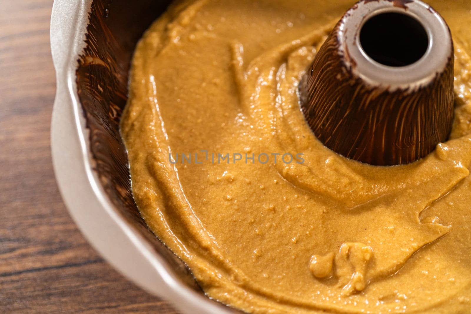 Pouring the gingerbread cake batter into the greased bundt cake pan, ready for a delightful caramel frosting.