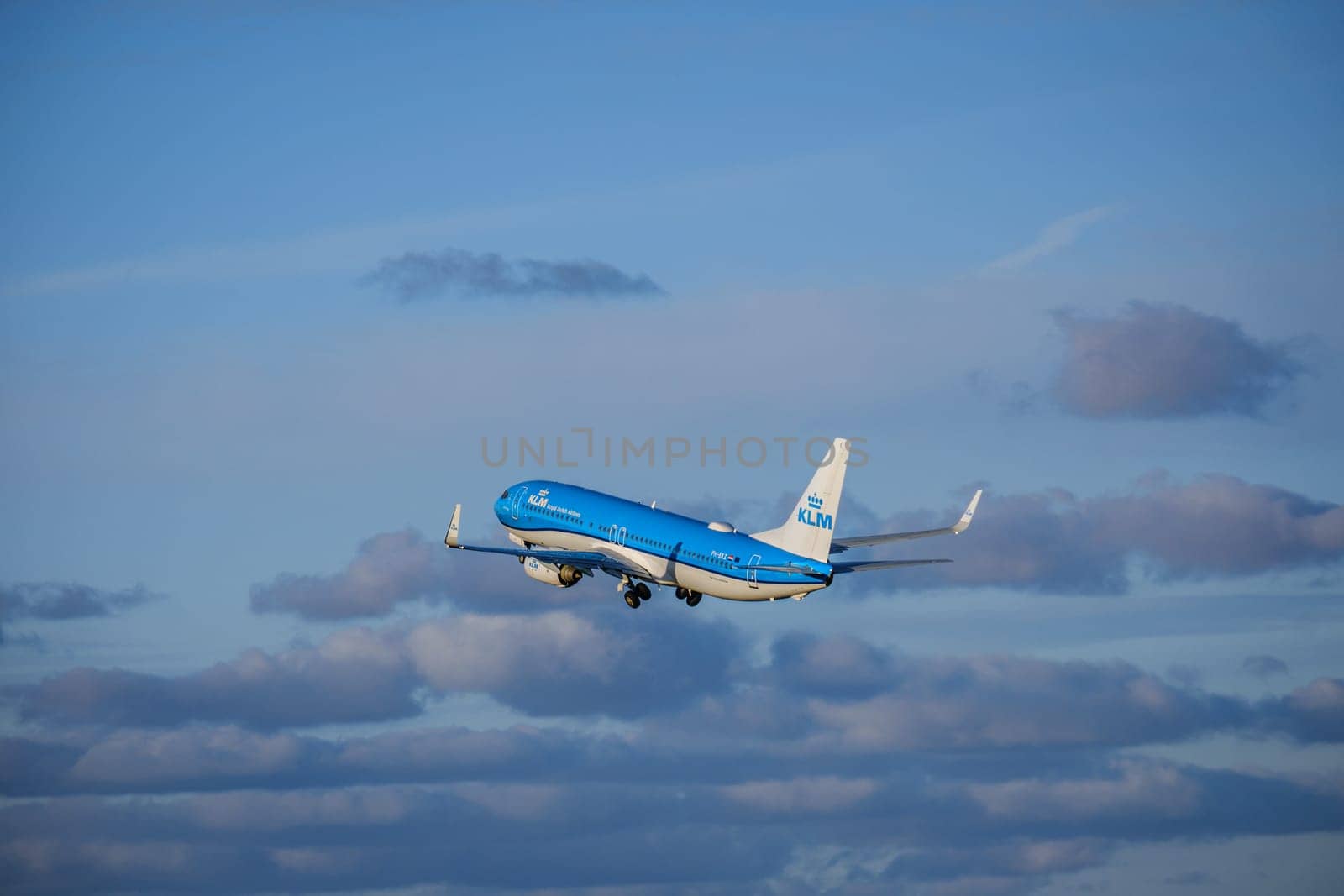 Lisbon, Portugal - Apr 29, 2024: KLM Royal Dutch Airlines aircraft Boeing 737-800 shot mid-flight, ascending into clear blue sky with some clouds, takeoff on sunny day. Vacations, travel, destinations, aircraft, low-cost airline, commercial flight