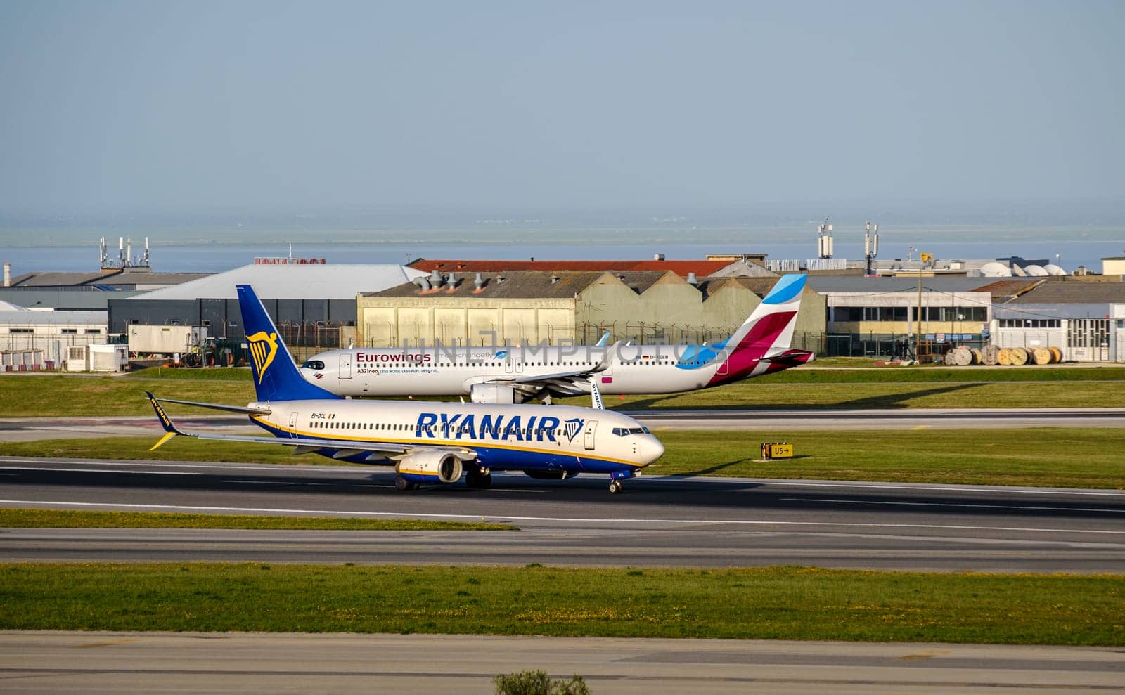 Lisbon, Portugal - Apr 3, 2024: Two commercial airplanes of Ryanair Boeing 737-800 and Eurowings Airbus A320 on Lisbon airport tarmac on sunny summer day, clear blue sky. Aircrafts taxiing, ready to depart, European travel hub, low-cost airlines