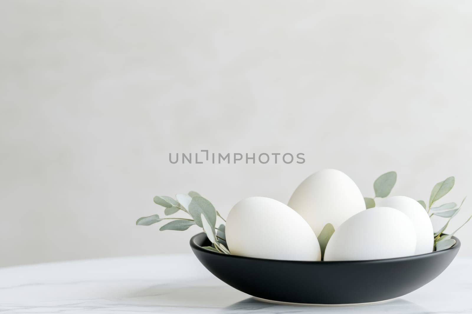This minimalist Easter centerpiece showcases white Easter eggs elegantly placed in a black bowl, accompanied by fresh eucalyptus leaves. It creates a serene and stylish decoration for the holiday.