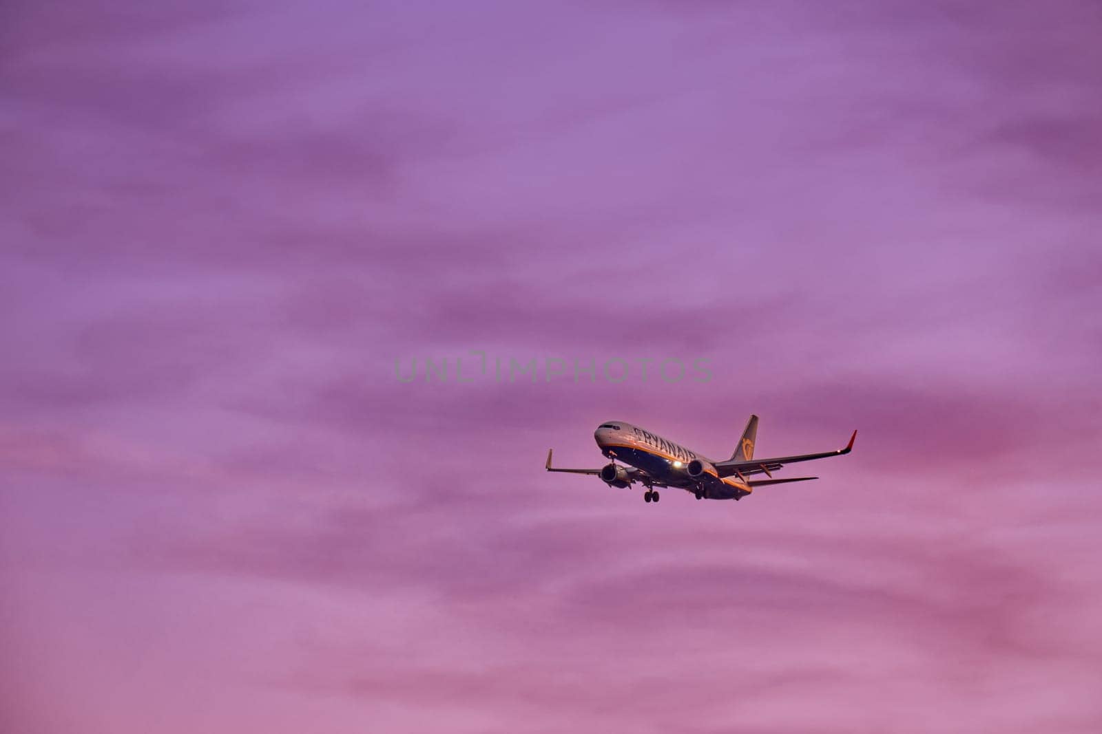 Lisbon, Portugal - Jan 14, 2025: Ryanair Boeing 737 aircraft shot mid-descent with landing gear extended, flying in sunset purple sky, some clouds. Airplane, low-cost airline, budget-friendly, European air travel, weekend getaway, summer vacations