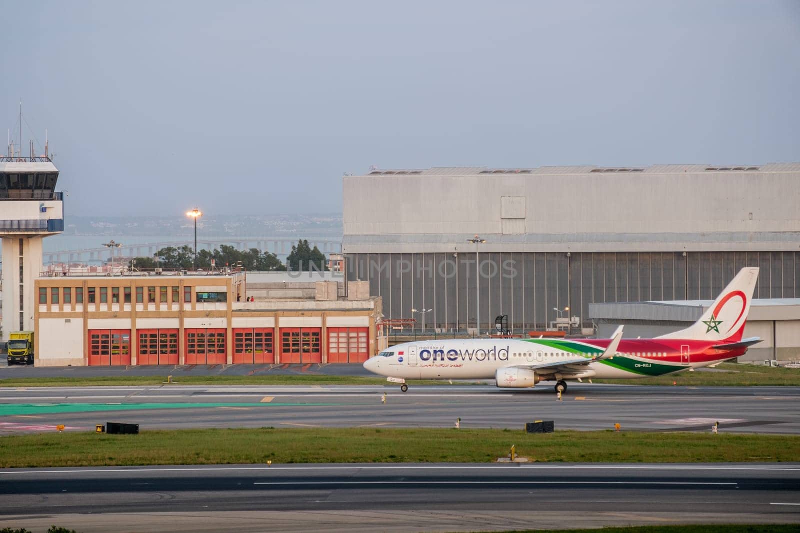 Lisbon, Portugal - Apr 3, 2024: Royal Air Maroc Boeing 737-800 airline aircraft taxiing on runway at Lisbon airport, clear sky, ATC control tower and hangars in background. Vacations,, summer travel destination, international hub, OneWorld group