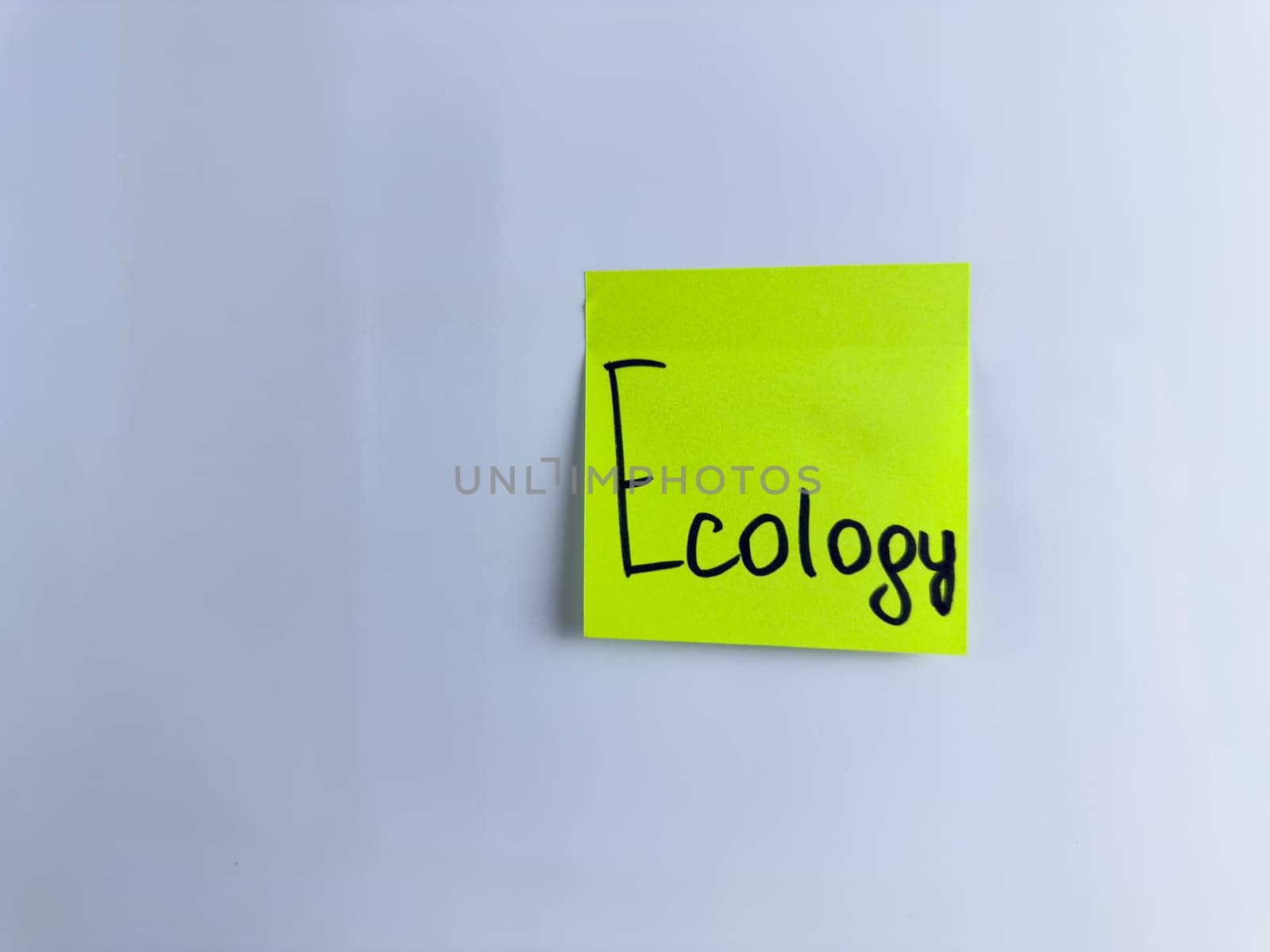 Handwritten word Ecology on green sticky note on white background. Environmental care and green technologies in modern world, ecological disasters and problems in nature