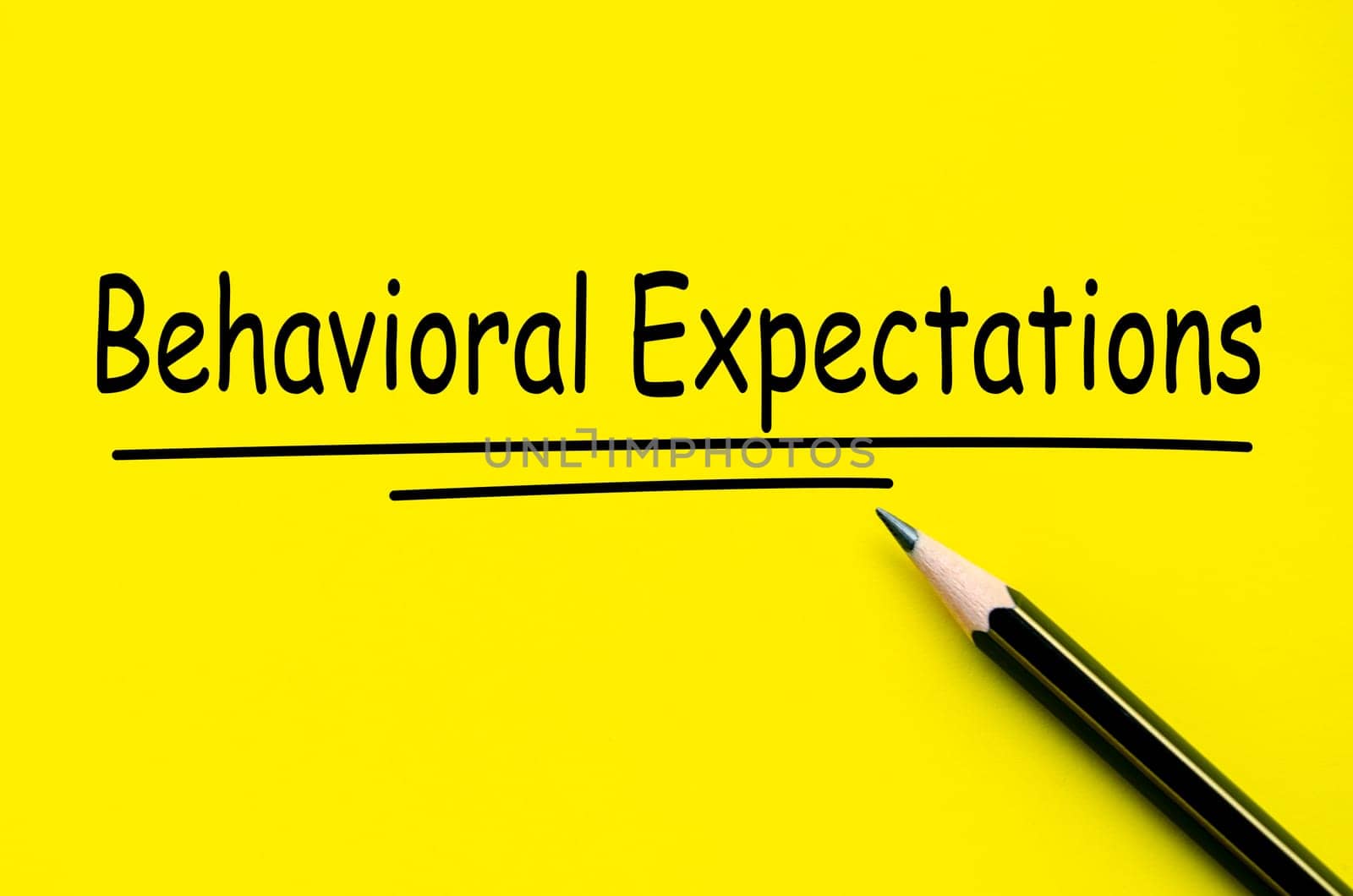 Behavioral Expectations text on yellow notepad with pencil background.