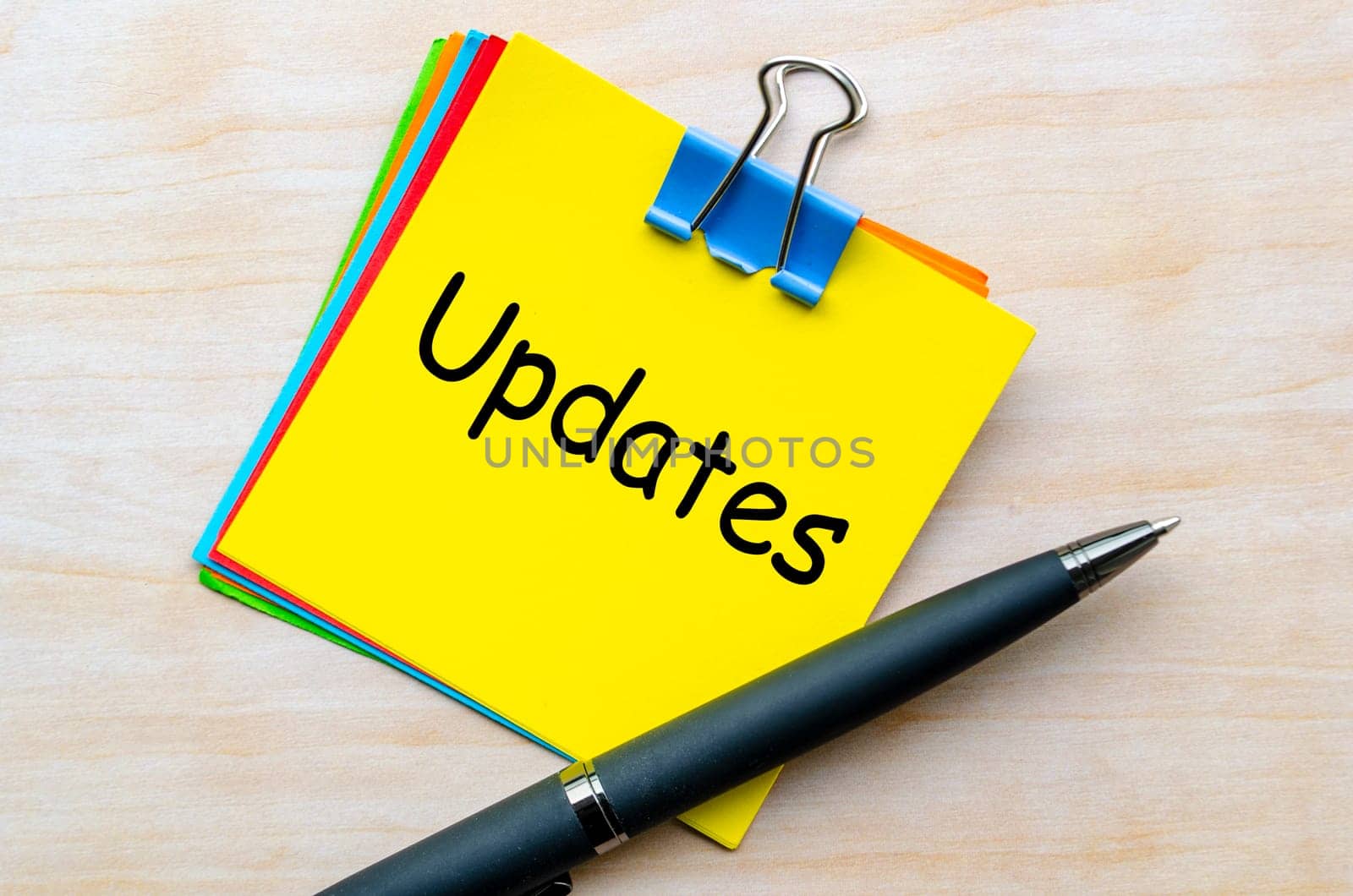 Updates text on yellow notepad with pen background.