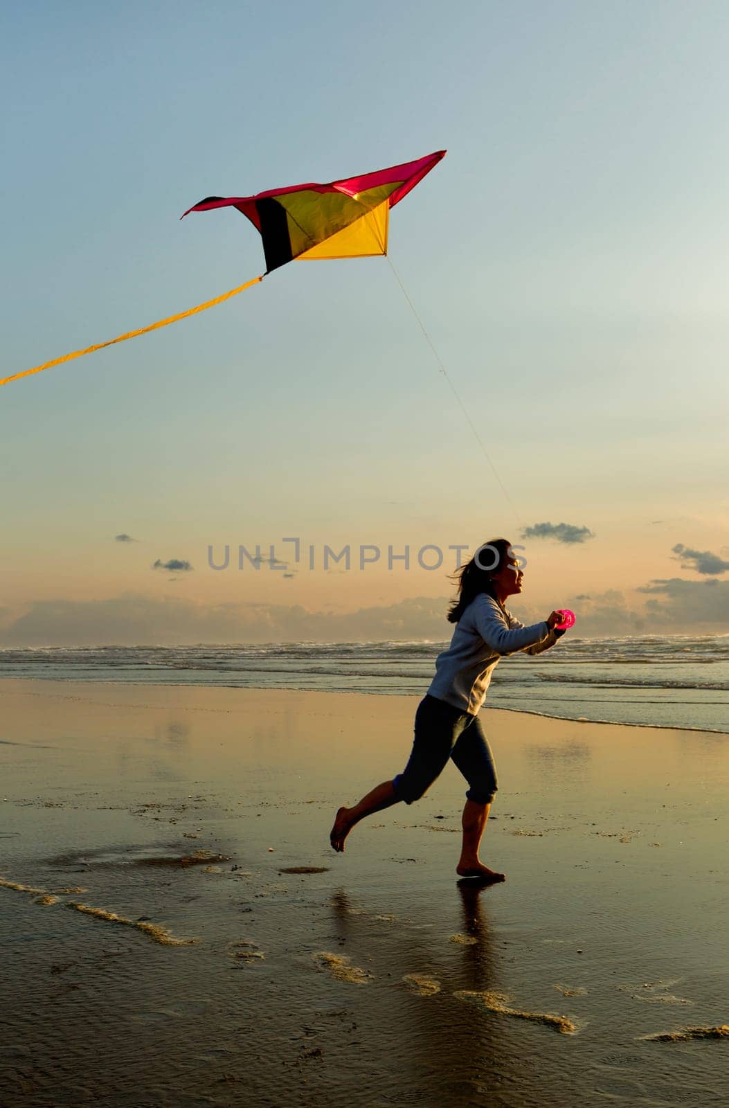 A woman flies a kite near sunset on the beach in Newport, Oregon.