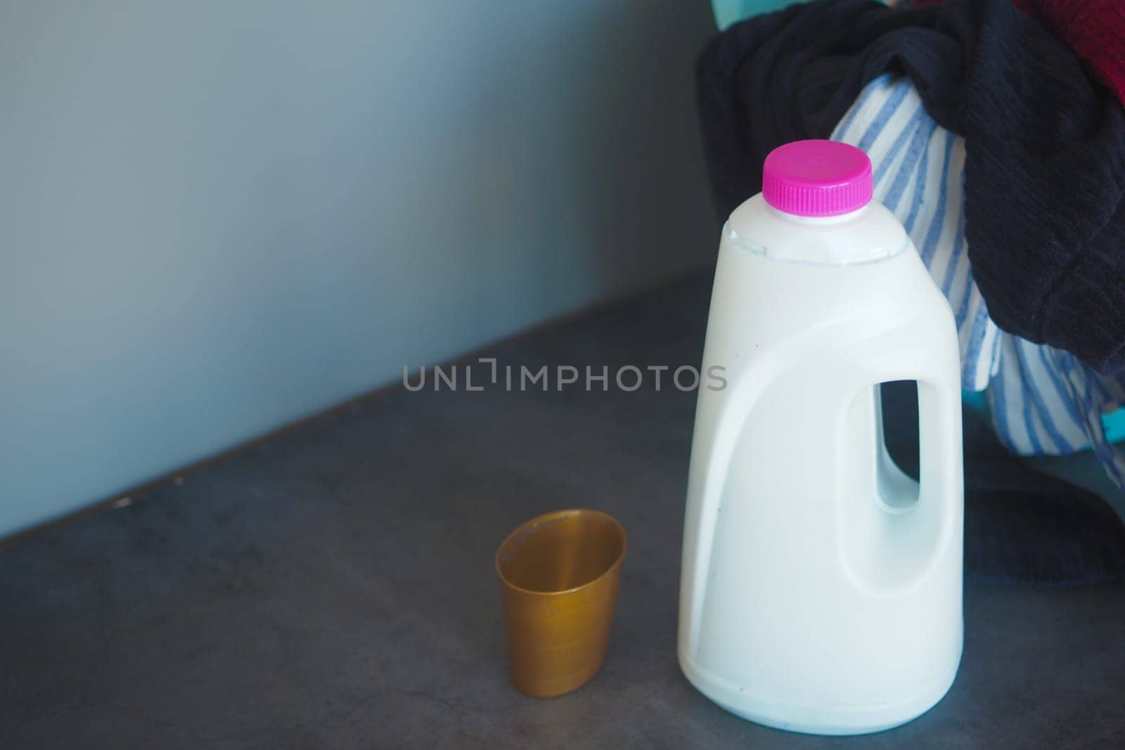 A white milk jug sits beside a small golden cup on a table.