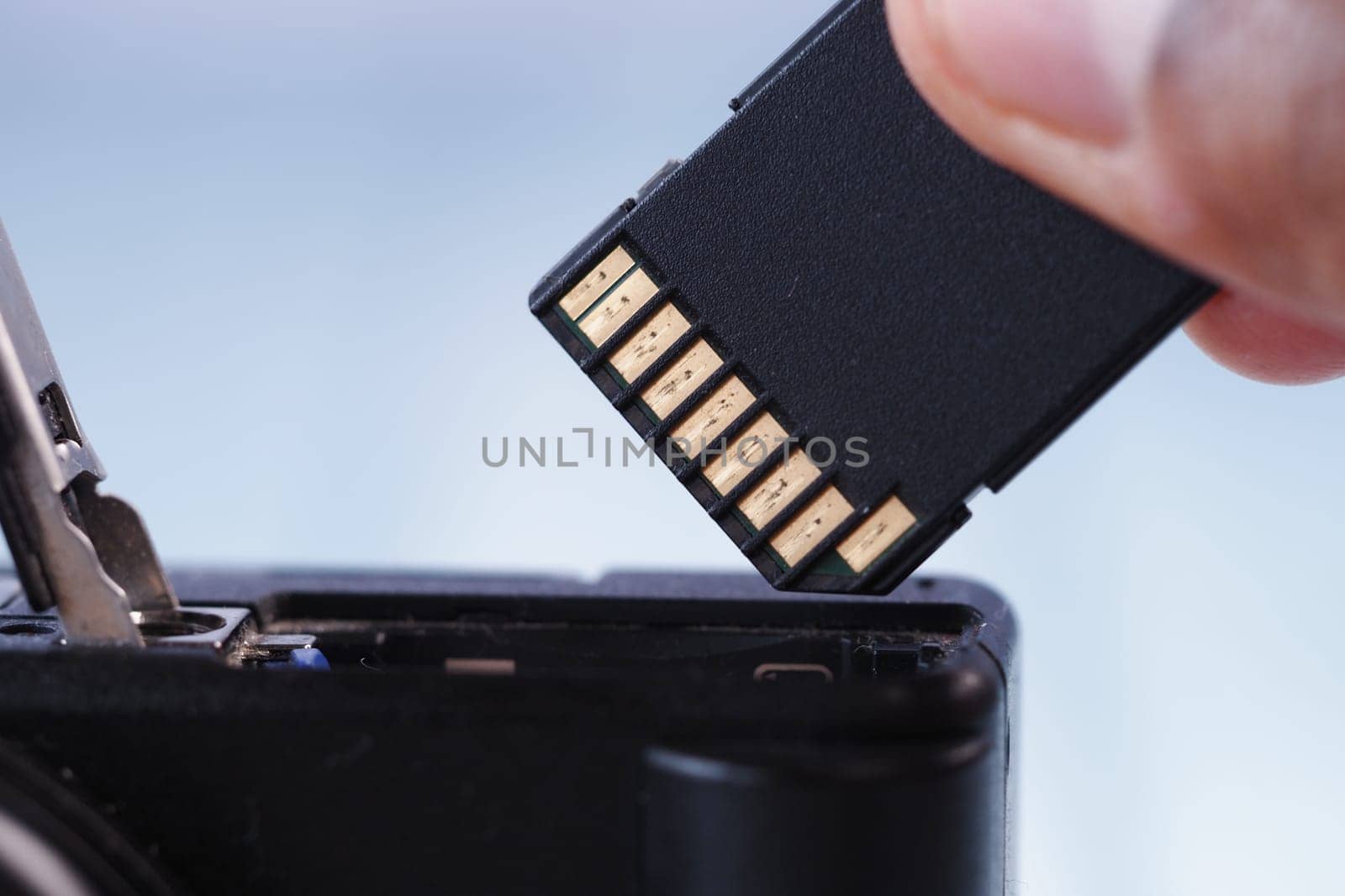 User carefully extracts a memory card from a camera for saving files.