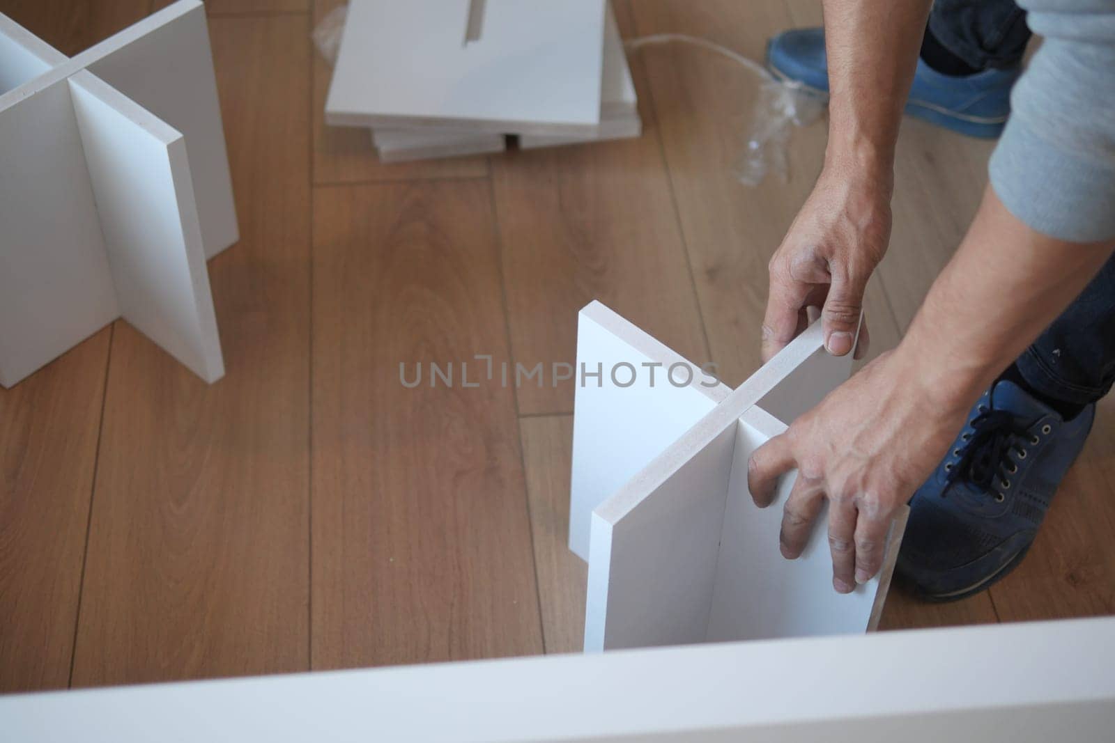 Individual is working on furniture assembly using white components.
