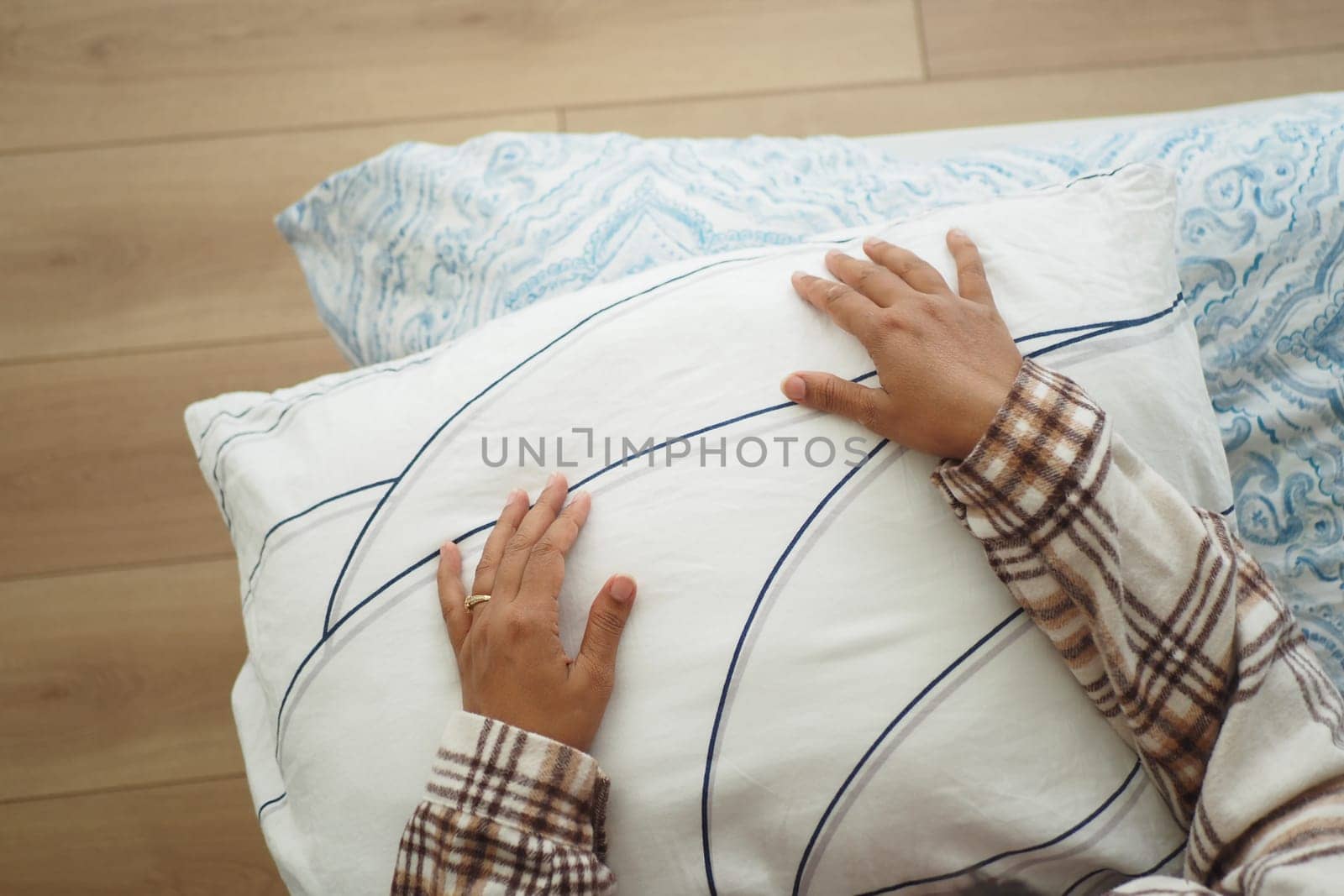 A person relaxes with hands on a soft pillow in a cozy bedroom.