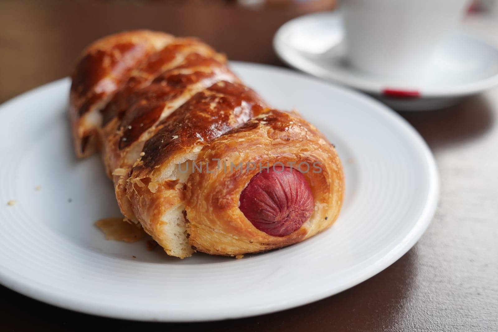 Freshly baked pastry with a savory sausage inside on a plate.