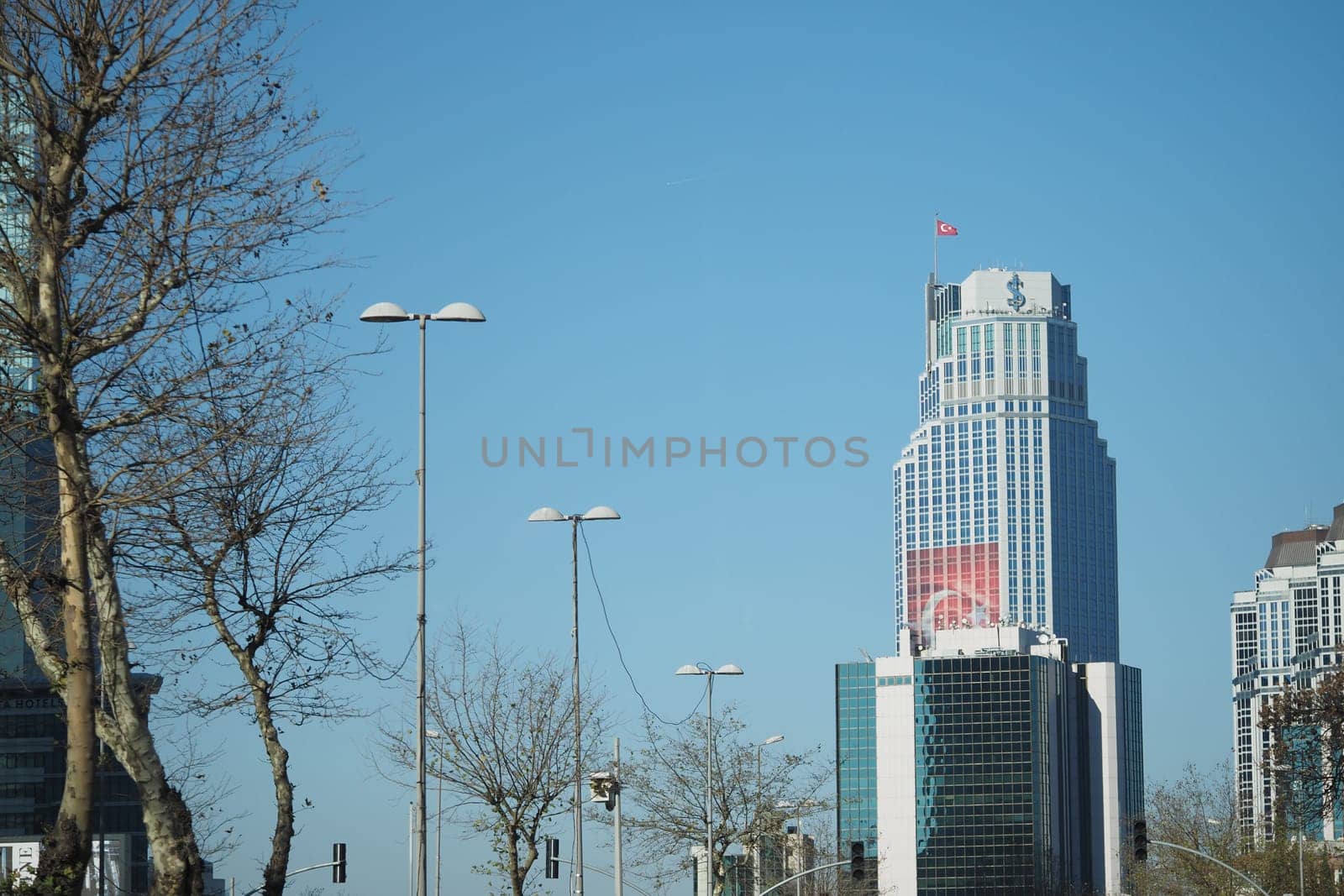 A tall building displays the Turkish flag against a clear sky.