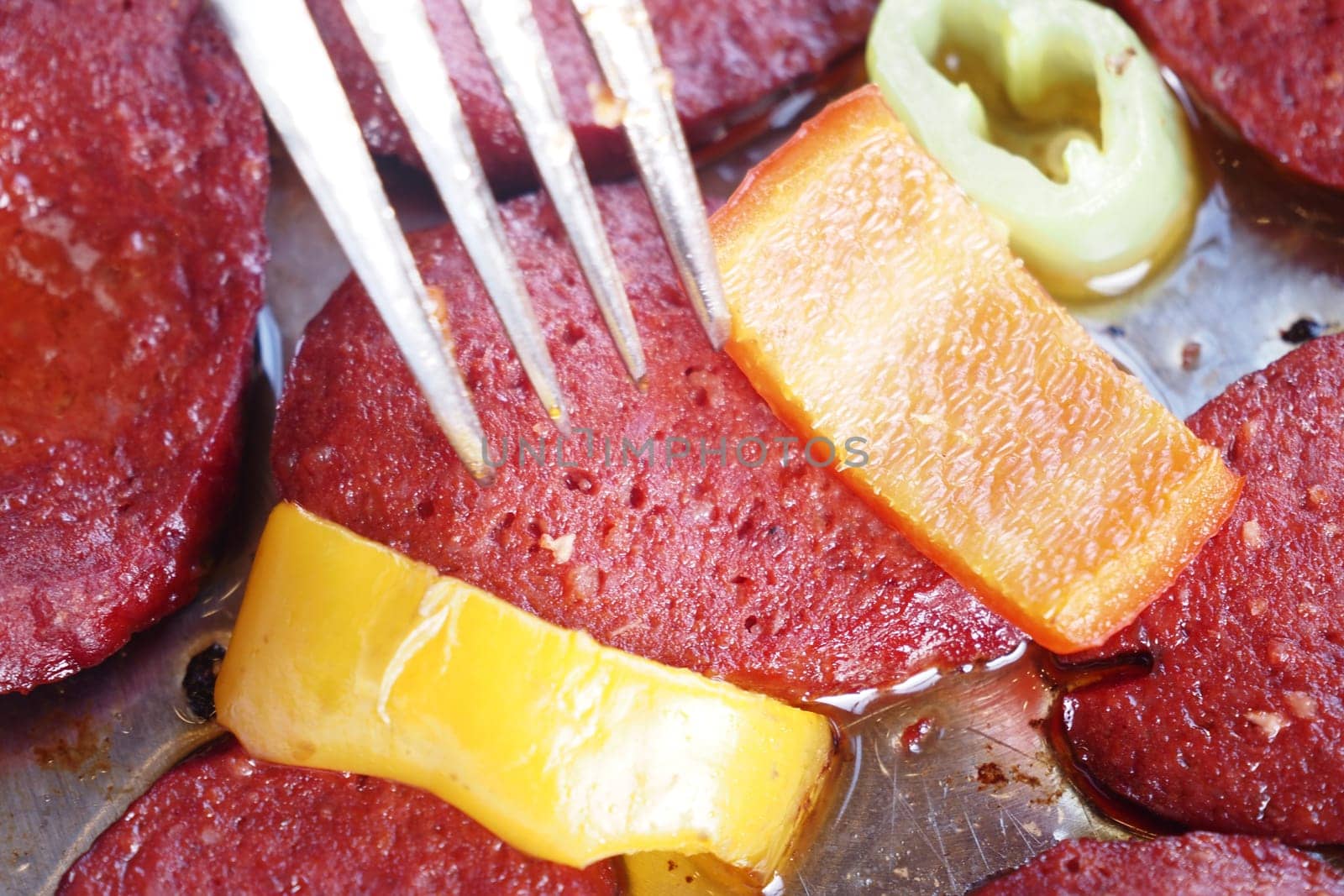 Juicy slices of sausage cooked with colorful peppers for a tasty dish.