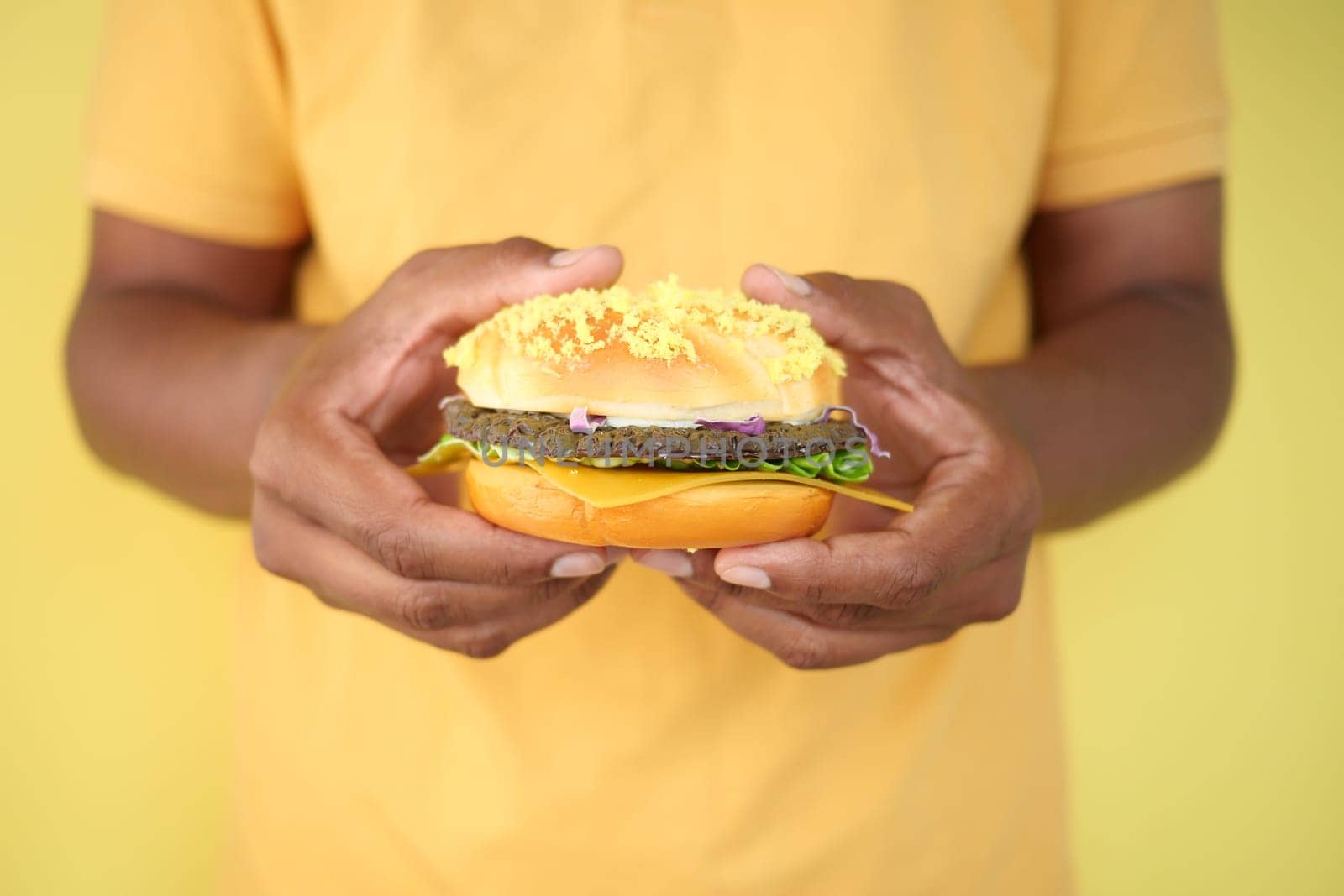 A person displays a vibrant burger with unique ingredients and toppings.