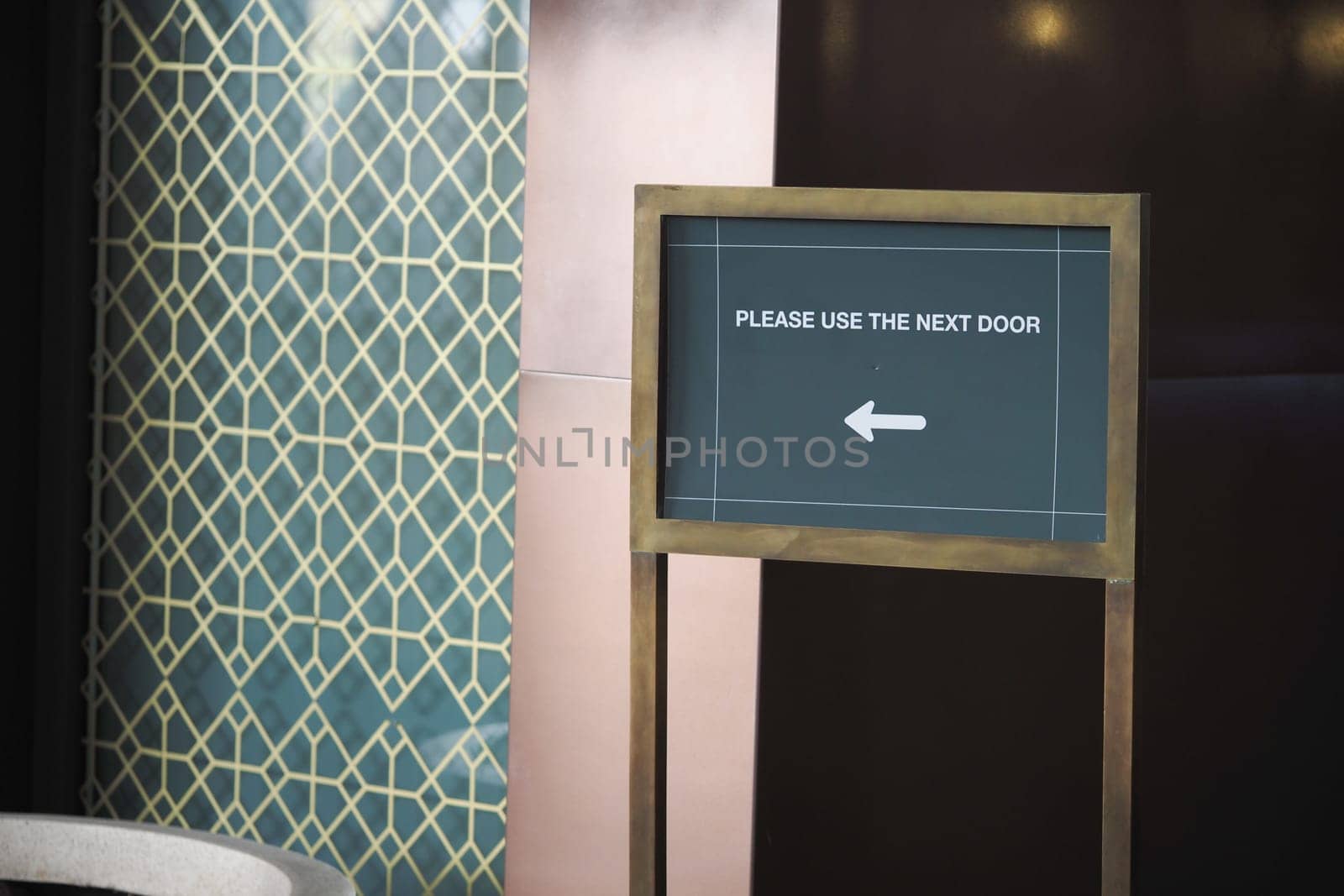 Wooden sign instructs people to use the next door with a clear arrow.
