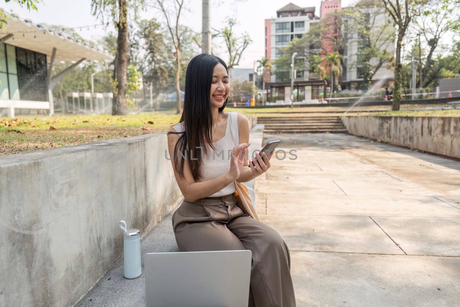 A joyful young woman engages with her smartphone, promoting a sustainable lifestyle in a beautiful outdoor environment.