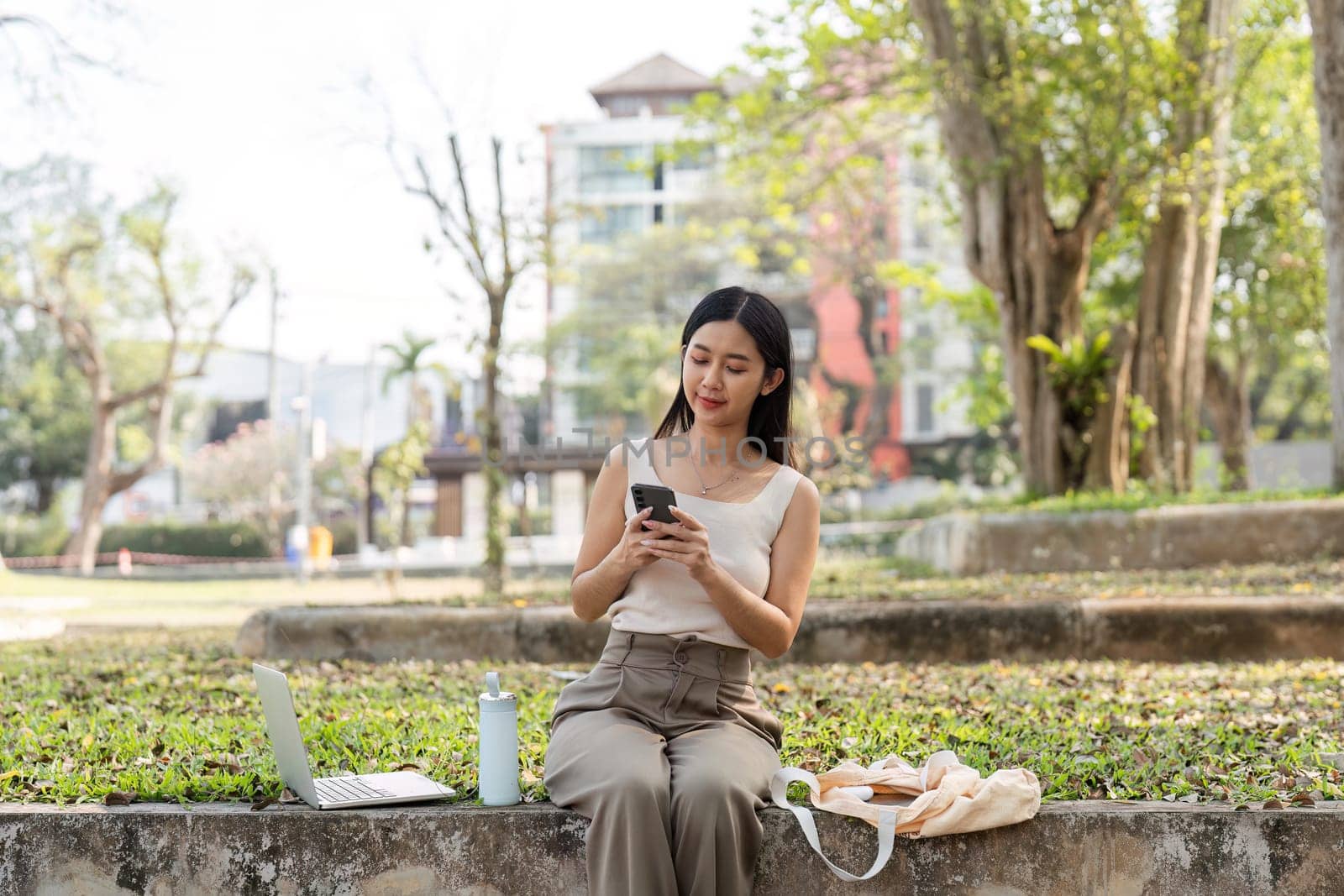 A young woman engages with her smartphone, embodying a sustainable lifestyle in a natural setting, showcasing modern connectivity.