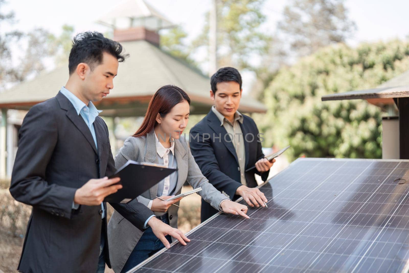 Three business professionals, including two men and one woman, engaging in discussions about the features of solar panels, emphasizing teamwork and commitment to sustainability.