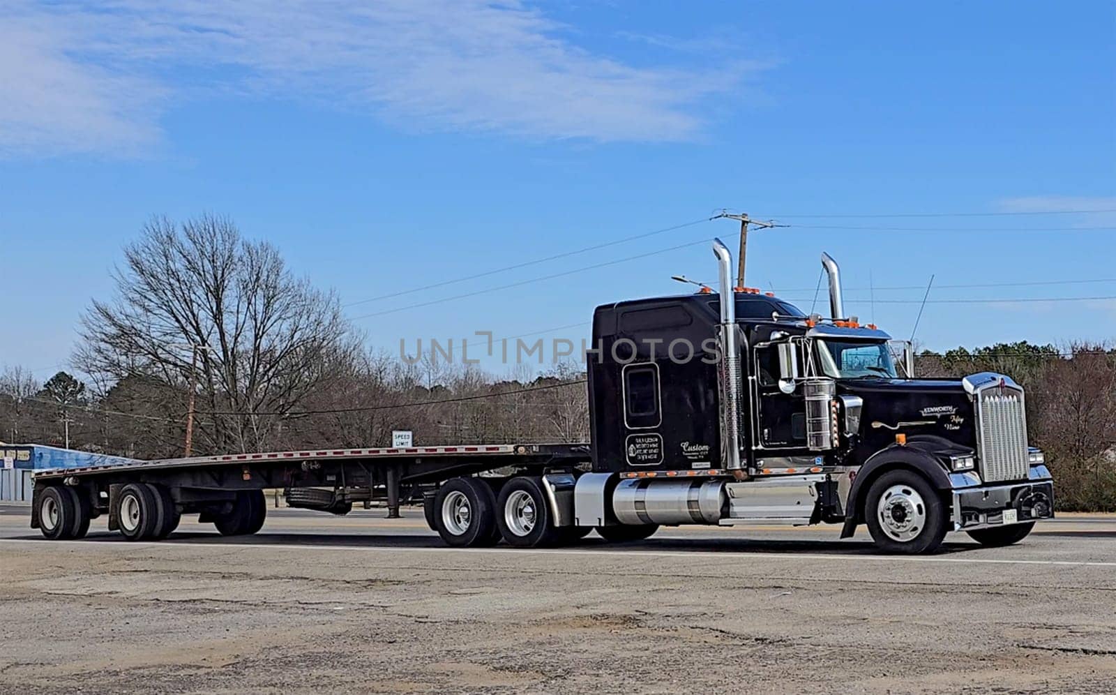 Freight liner Semi-Truck Driving on Open Highway in a Rural Area, CDL Truck America, semi truck and trailer travels along an open road under a blue sky in a rustic rural setting, showcasing commercial transportation, logistics efficiency, and professional trucking