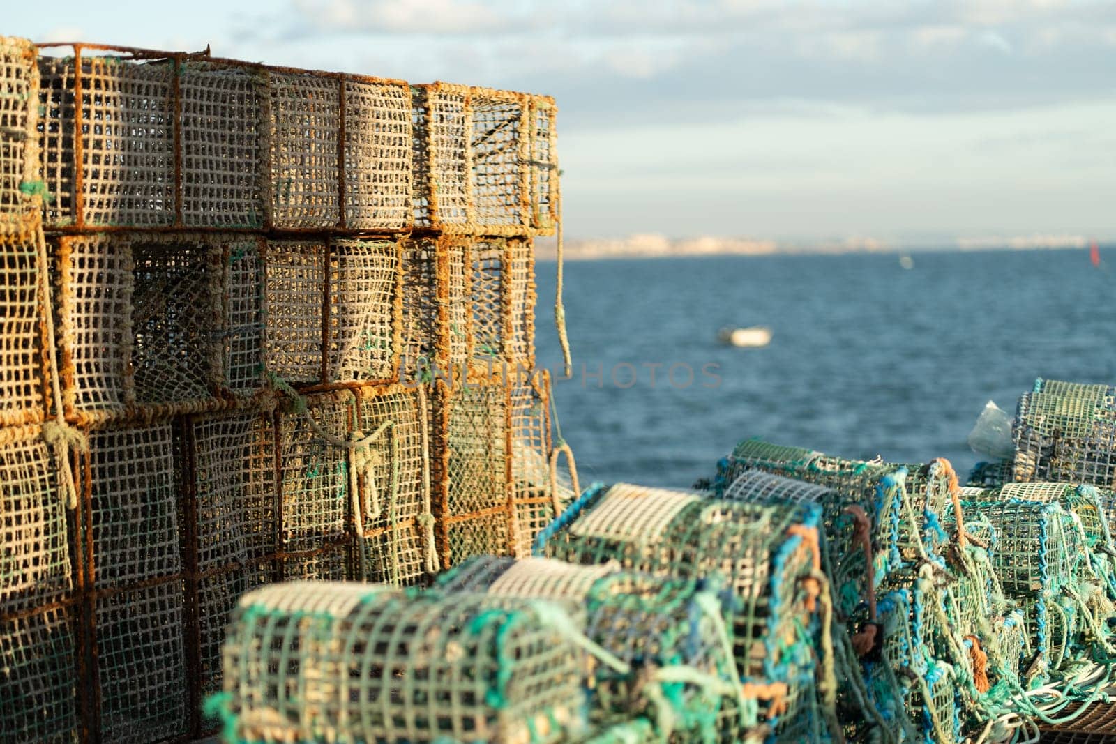 Stack of traditional lobster traps on coastal waterfront, used for capture fisheries and seafood collection, with ocean in background
