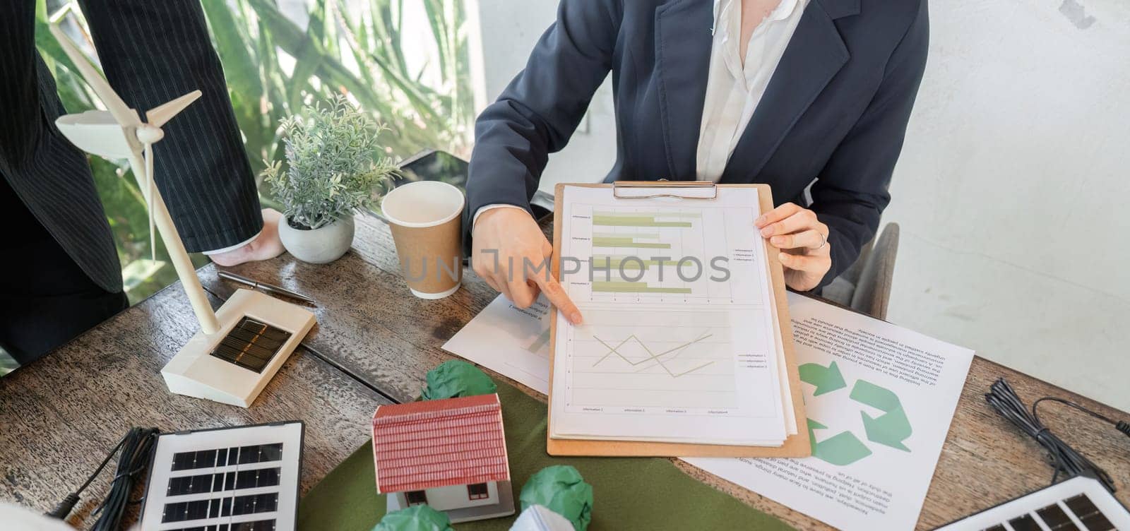 A focused meeting discusses renewable energy strategies as one professional points to data charts, emphasizing the importance of evidence-based decision-making in eco-friendly development.