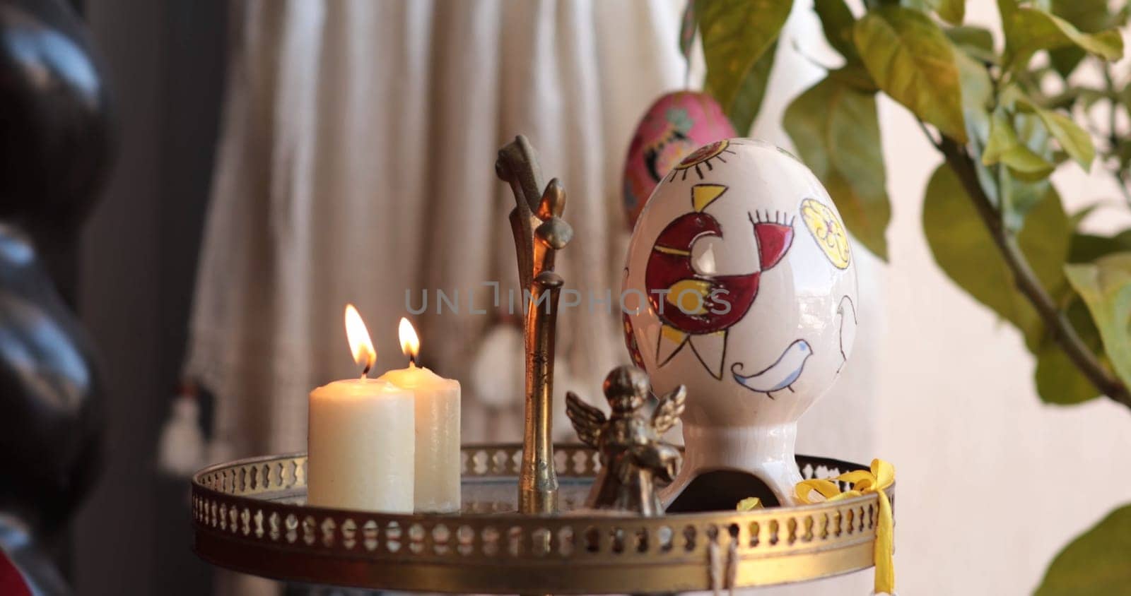 Handcrafted Easter decorations brighten the setting with a colorful egg, lit candles, and charming ornaments, perfect for celebrating the Easter holiday with joy and warmth.