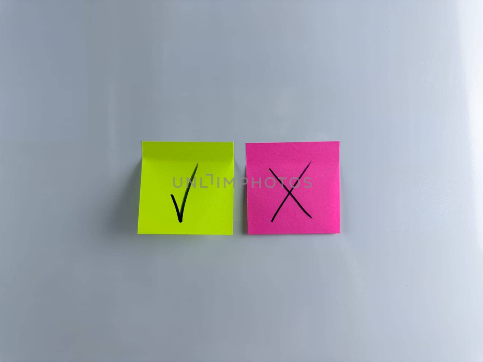 Choosing answer and marking it with tick or cross. Handwritten tick and cross on sticky note on white background. Conceptual photo of choosing an answer or making an important decision